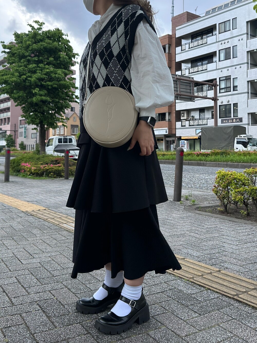 ブラック系のローファー、ブラック系のスカート、ホワイト系のショルダーバッグを着用したレディースの春コーディネートの2枚目の写真