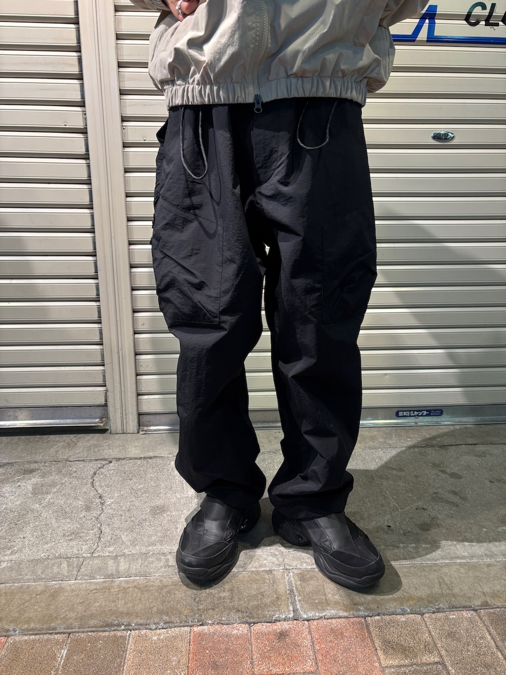 ホワイト系のナイロンジャケット、ブラック系のその他パンツを着用したメンズの春コーディネートの3枚目の写真