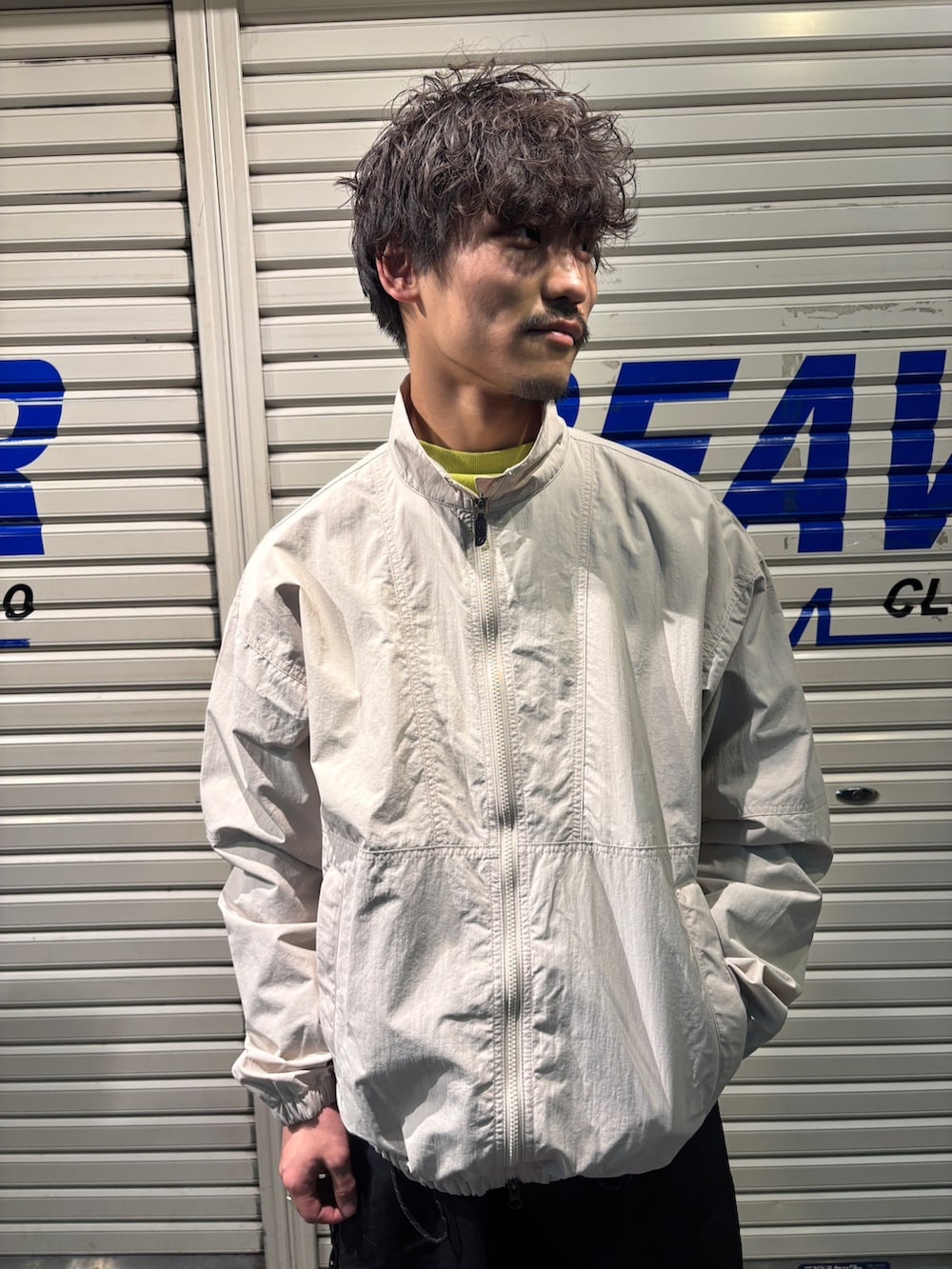 ホワイト系のナイロンジャケット、ブラック系のその他パンツを着用したメンズの春コーディネートの2枚目の写真