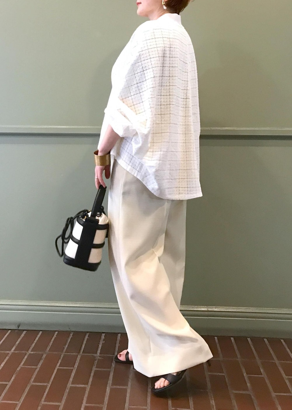 ブラック系のハンドバッグ、ブラック系のサンダル、ホワイト系のブルゾンを着用したレディースの春コーディネートの5枚目の写真