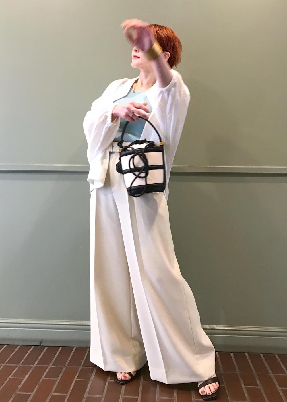 ブラック系のハンドバッグ、ブラック系のサンダル、ホワイト系のブルゾンを着用したレディースの春コーディネートの2枚目の写真