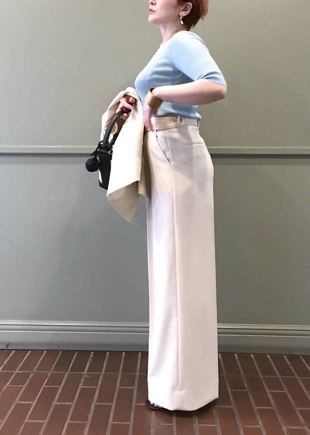 ブラック系のハンドバッグ、ブラック系のサンダル、ホワイト系のベストを着用したレディースの春コーディネートの6枚目の写真