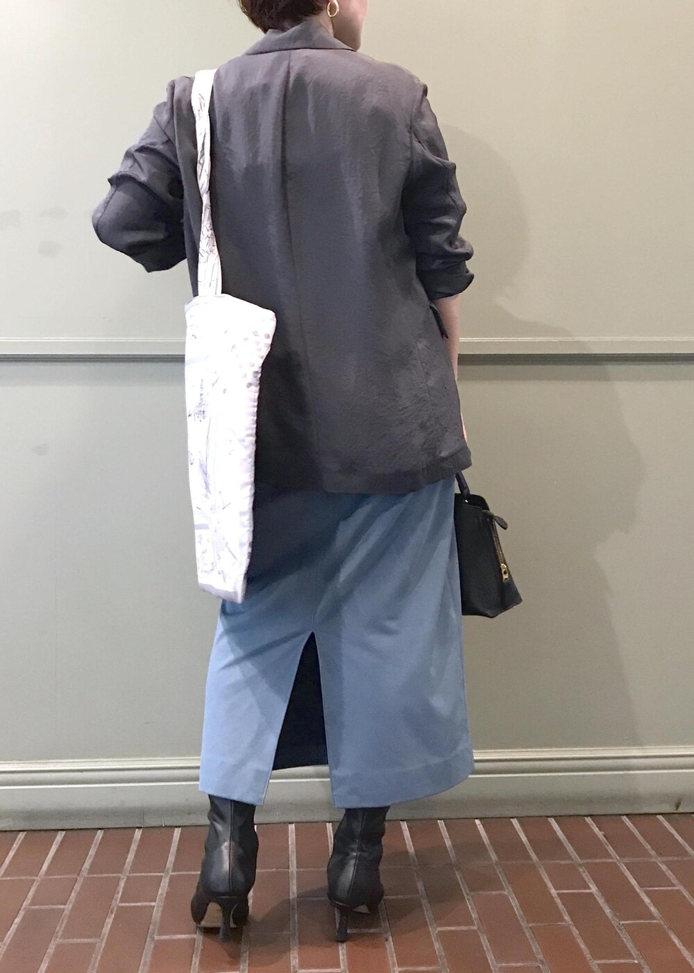 ブルー系のスカート、ホワイト系のトートバッグ、グレー系のテーラードジャケットを着用したレディースの秋コーディネートの3枚目の写真