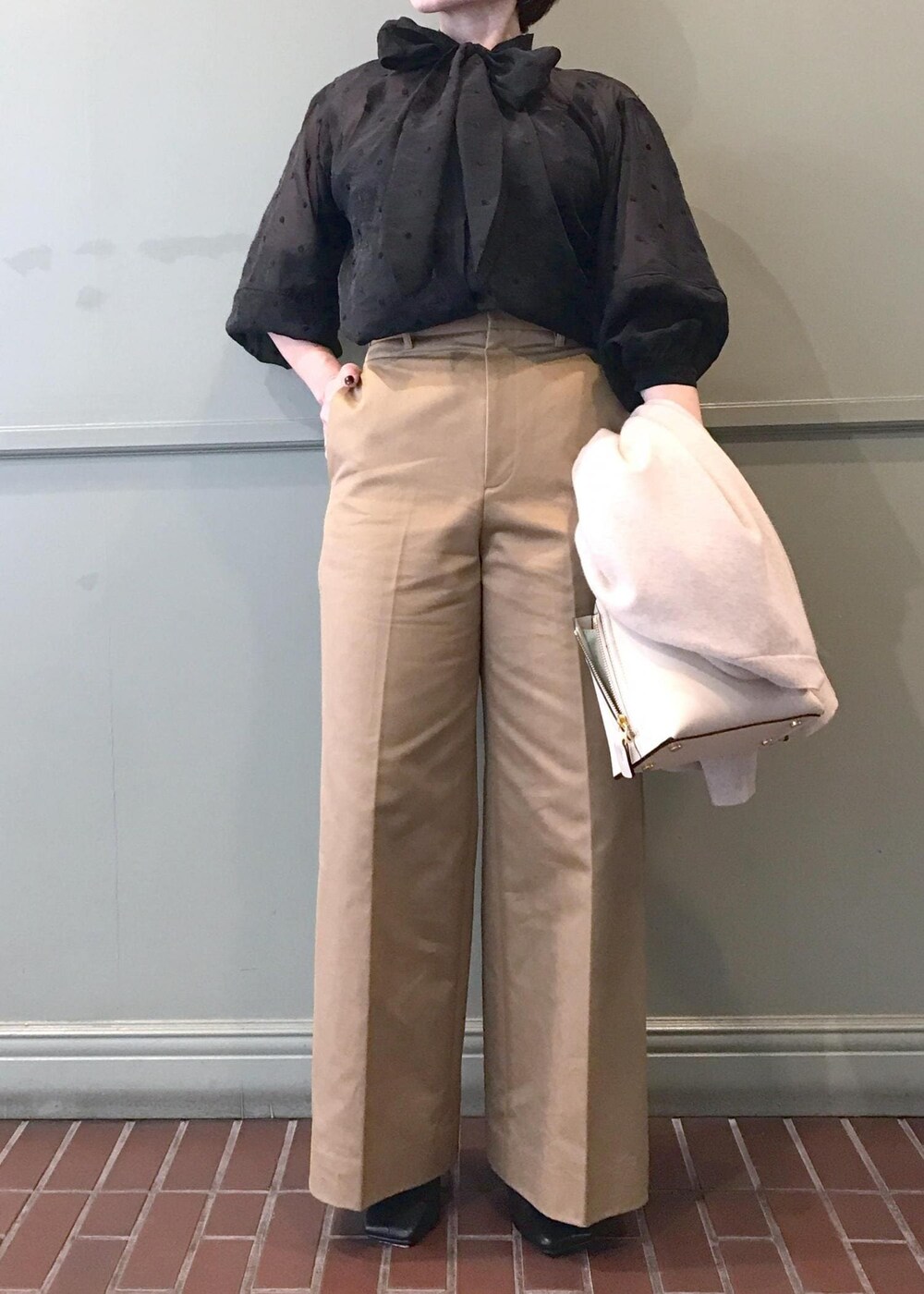 ホワイト系のハンドバッグ、ブラック系のブーツ、ベージュ系のチノパンツを着用したレディースの秋コーディネートの6枚目の写真