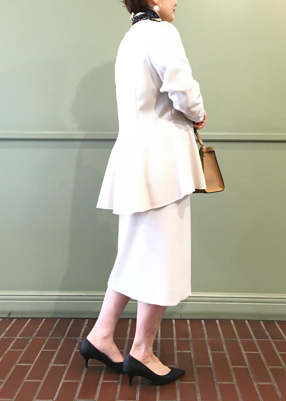 ブラック系のパンプス、ベージュ系のショルダーバッグ、ベージュ系のスカートを着用したレディースの冬コーディネートの3枚目の写真