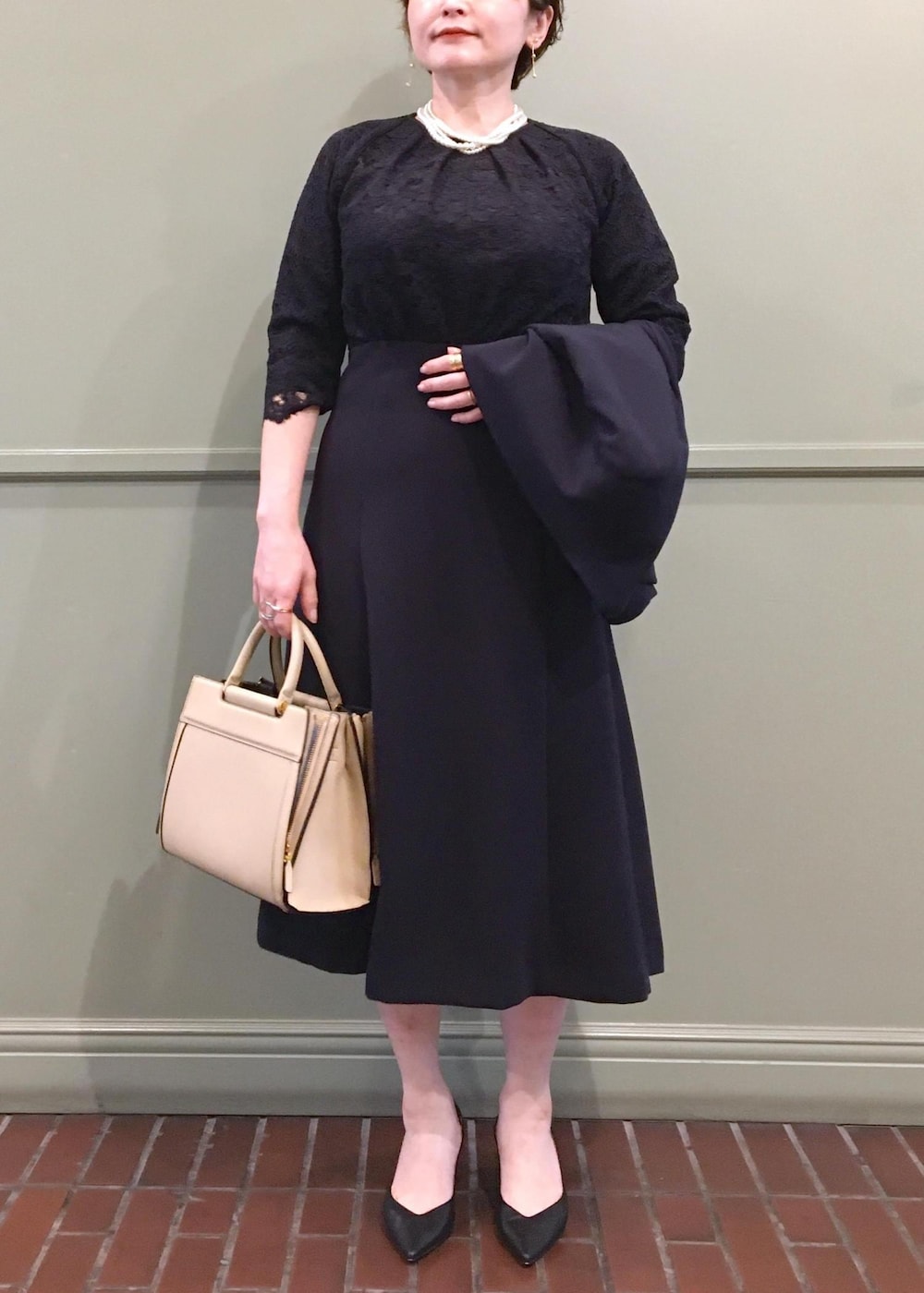 ベージュ系のハンドバッグ、ブルー系のワンピース、ブルー系のノーカラージャケットを着用したレディースの冬コーディネートの2枚目の写真