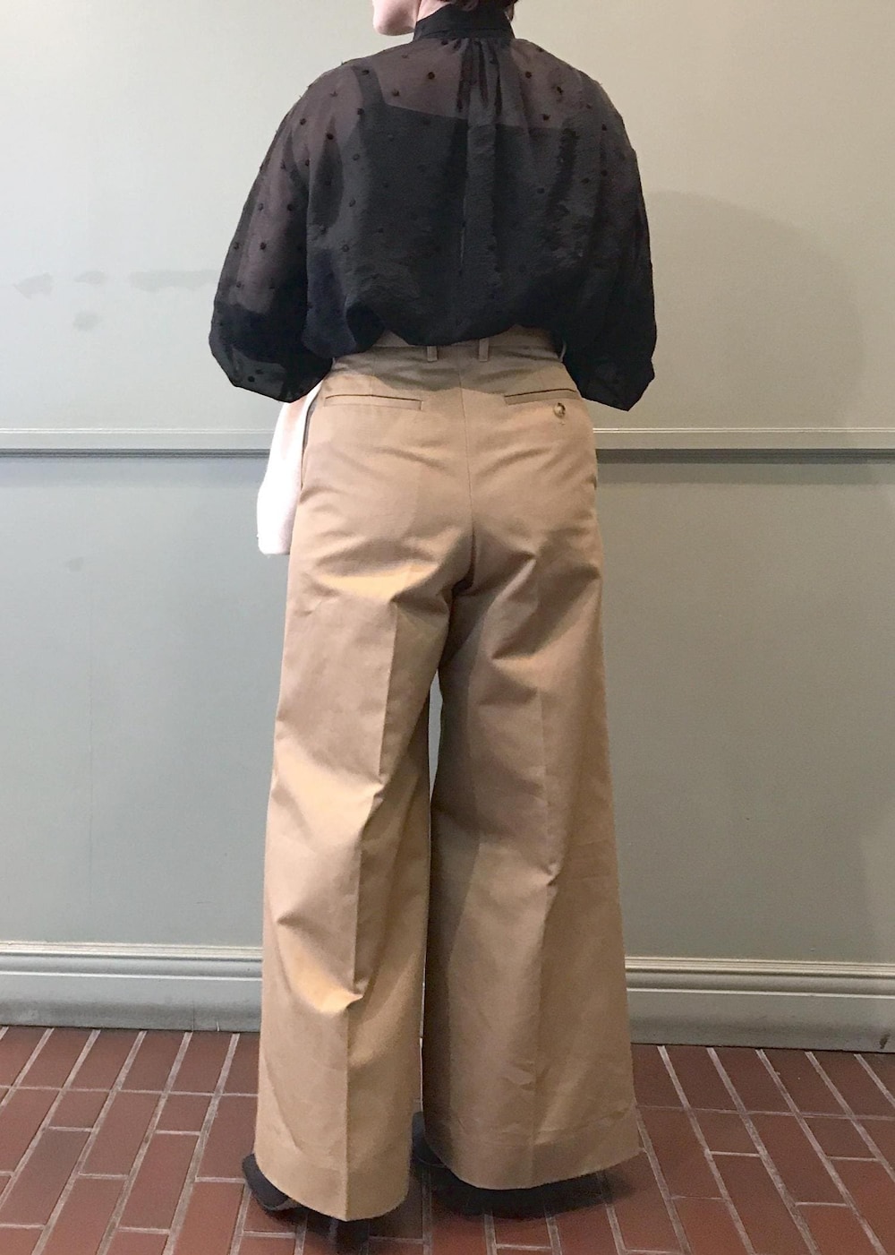 ホワイト系のハンドバッグ、ブラック系のブーツ、ベージュ系のチノパンツを着用したレディースの秋コーディネートの8枚目の写真