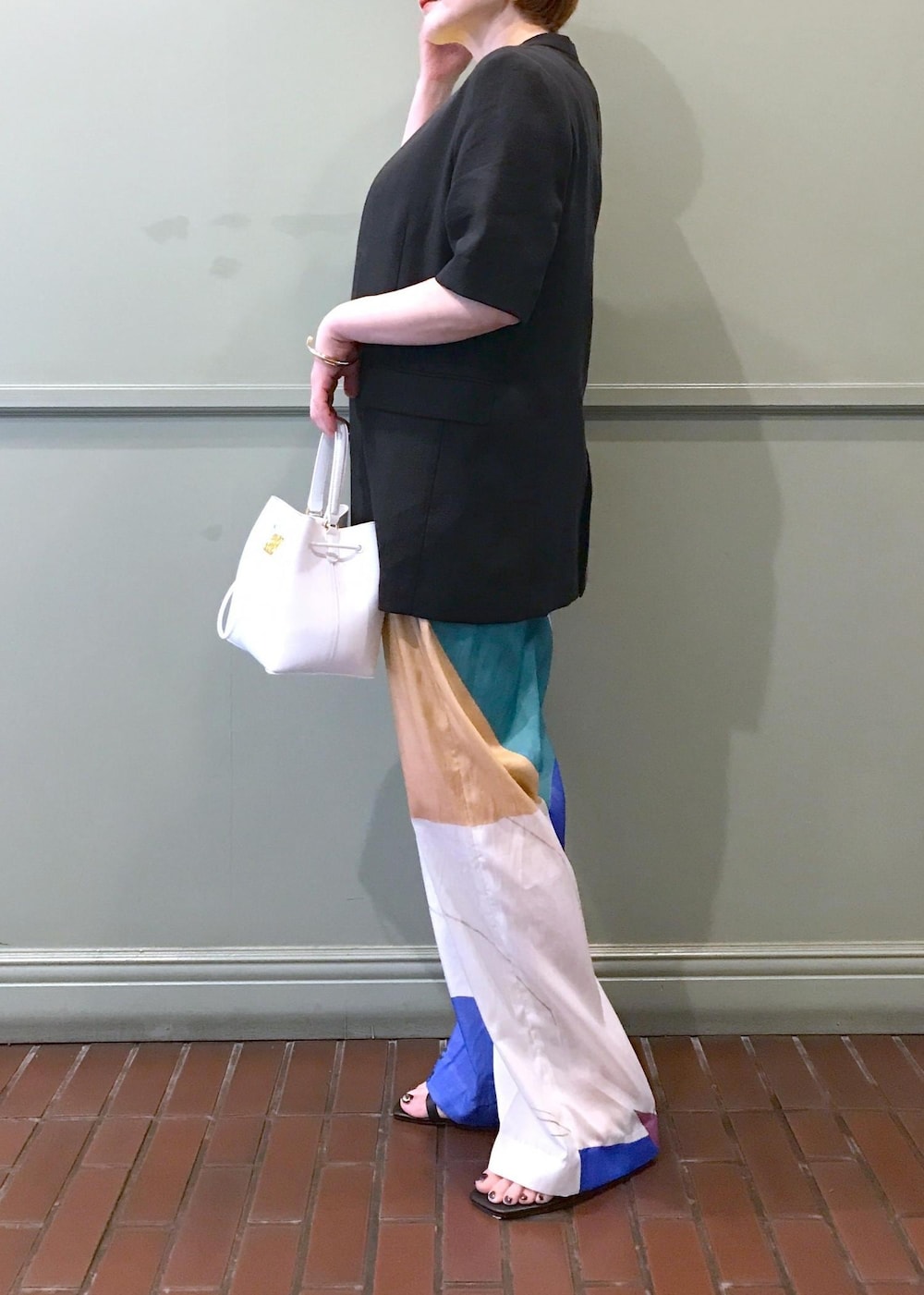 ホワイト系のハンドバッグ、ブラック系のサンダル、イエロー系のニット/セーターを着用したレディースの春コーディネートの2枚目の写真