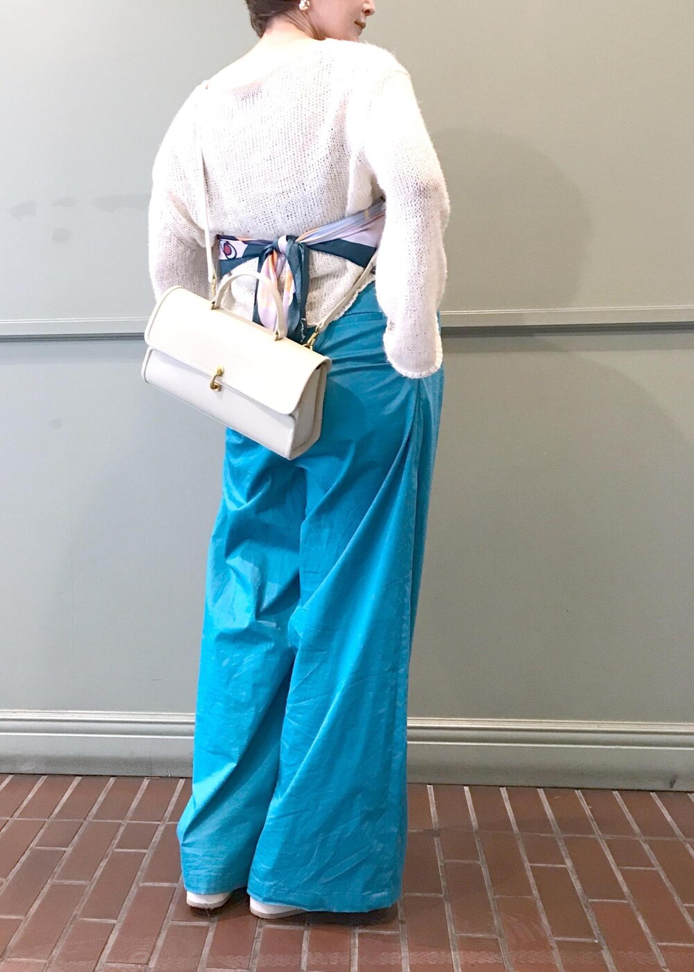 ベージュ系のショルダーバッグ、ホワイト系のニット/セーター、ブルー系のつなぎ/オールインワンを着用したレディースの春コーディネートの4枚目の写真