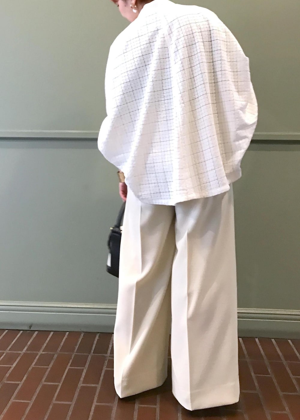 ブラック系のハンドバッグ、ブラック系のサンダル、ホワイト系のブルゾンを着用したレディースの春コーディネートの4枚目の写真