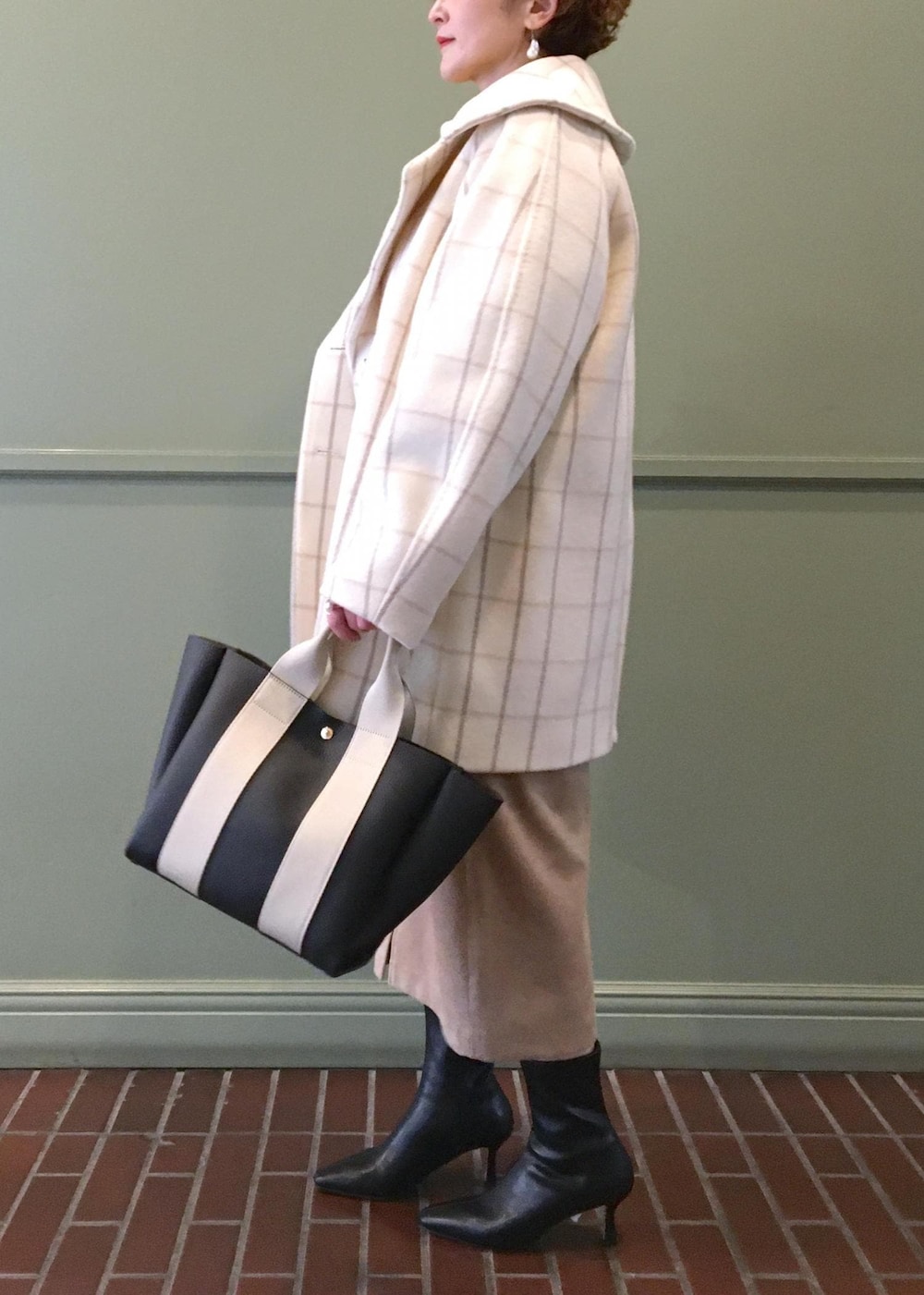 ブラック系のトートバッグ、ブラック系のブーツ、ホワイト系のチェスターコートを着用したレディースの秋コーディネートの2枚目の写真