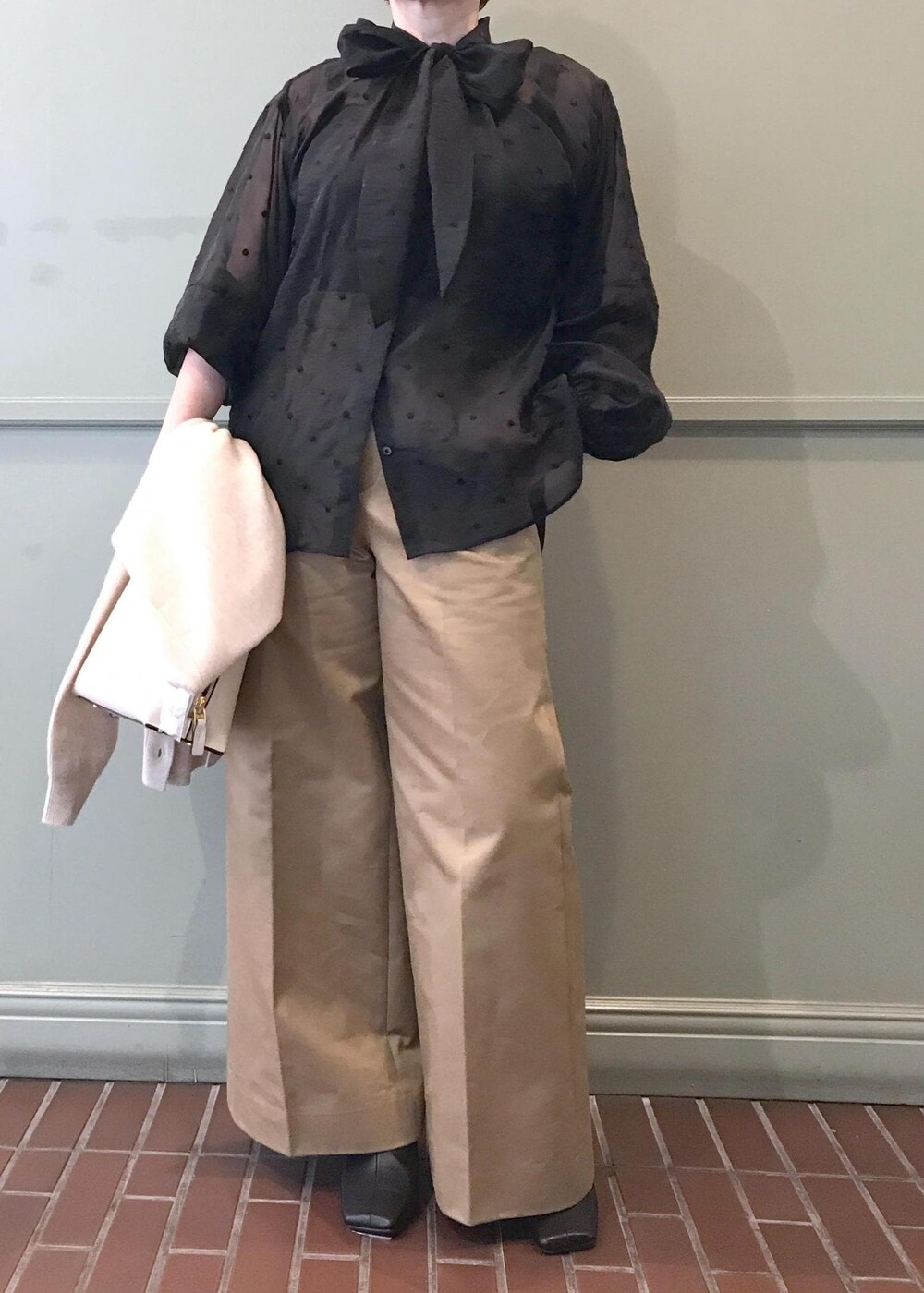 ホワイト系のハンドバッグ、ブラック系のブーツ、ベージュ系のチノパンツを着用したレディースの秋コーディネートの9枚目の写真