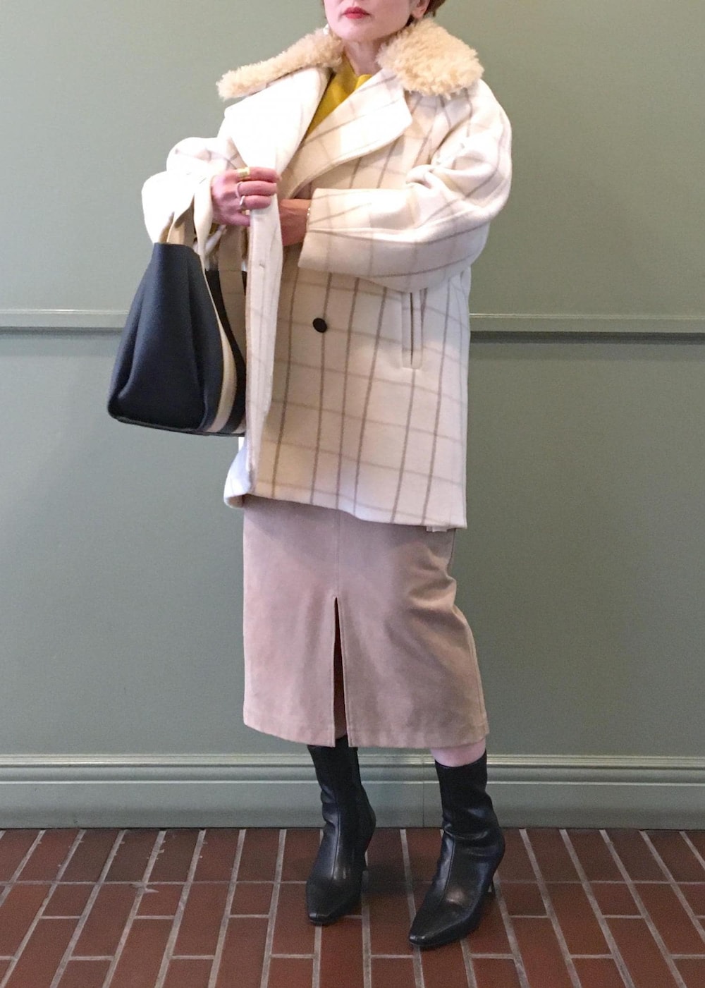 ブラック系のトートバッグ、ブラック系のブーツ、ホワイト系のチェスターコートを着用したレディースの秋コーディネートの6枚目の写真