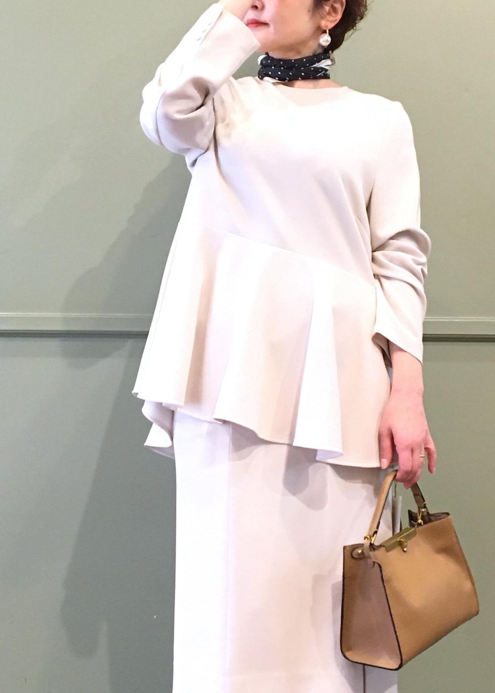 ブラック系のパンプス、ベージュ系のショルダーバッグ、ベージュ系のスカートを着用したレディースの冬コーディネートの4枚目の写真