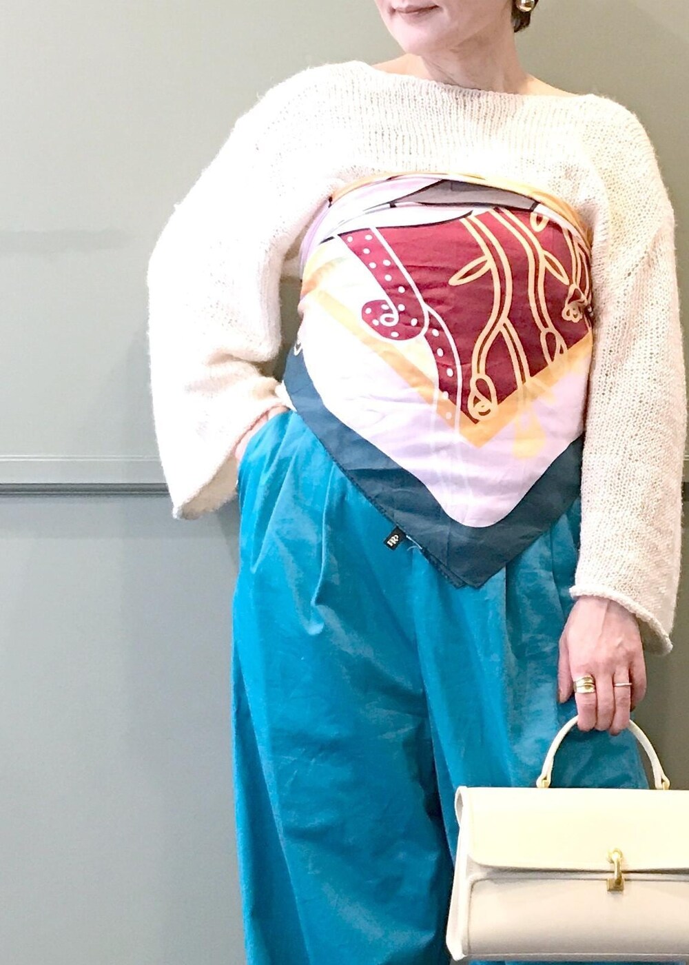 ベージュ系のショルダーバッグ、ホワイト系のニット/セーター、ブルー系のつなぎ/オールインワンを着用したレディースの春コーディネートの6枚目の写真