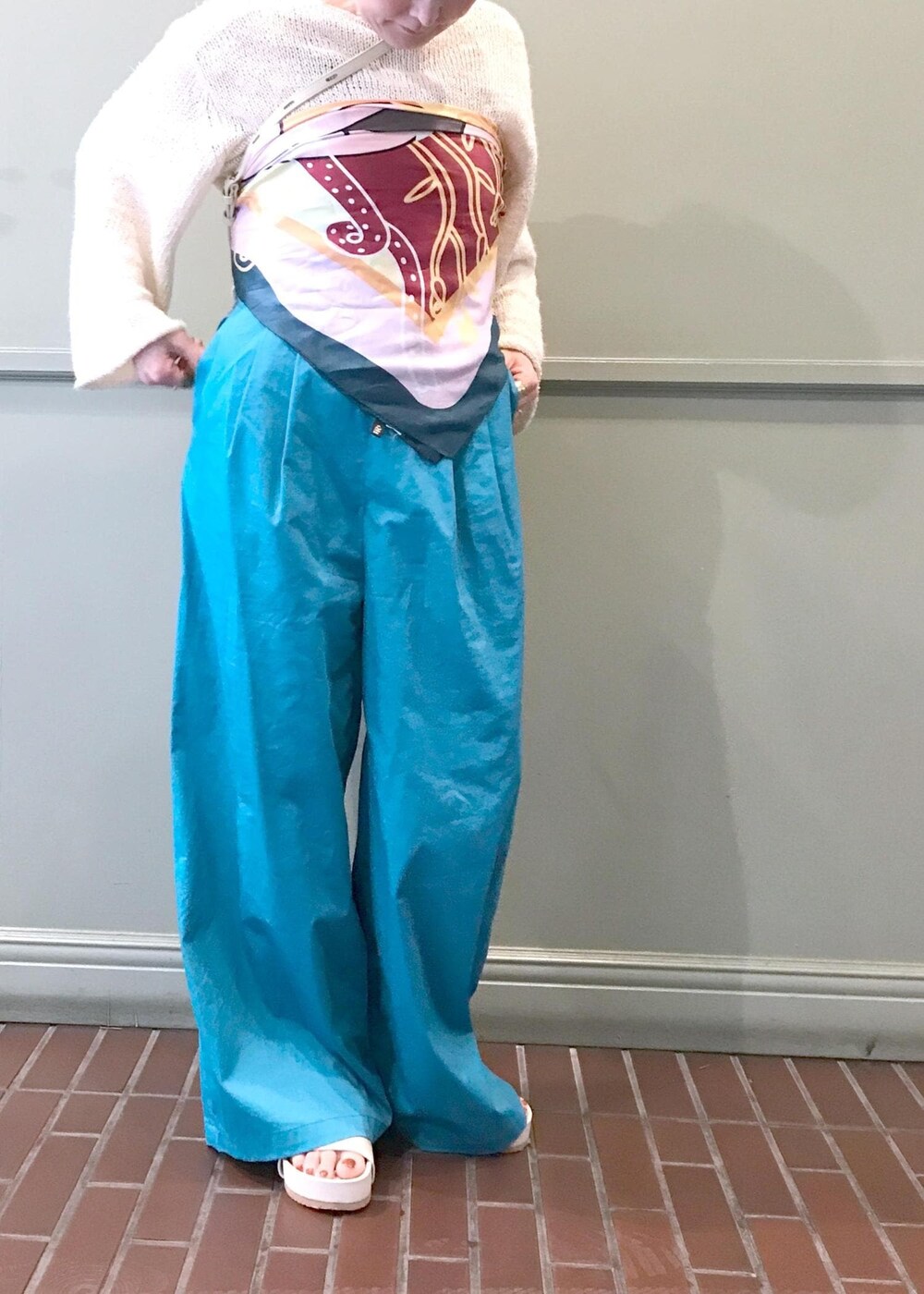 ベージュ系のショルダーバッグ、ホワイト系のニット/セーター、ブルー系のつなぎ/オールインワンを着用したレディースの春コーディネートの3枚目の写真