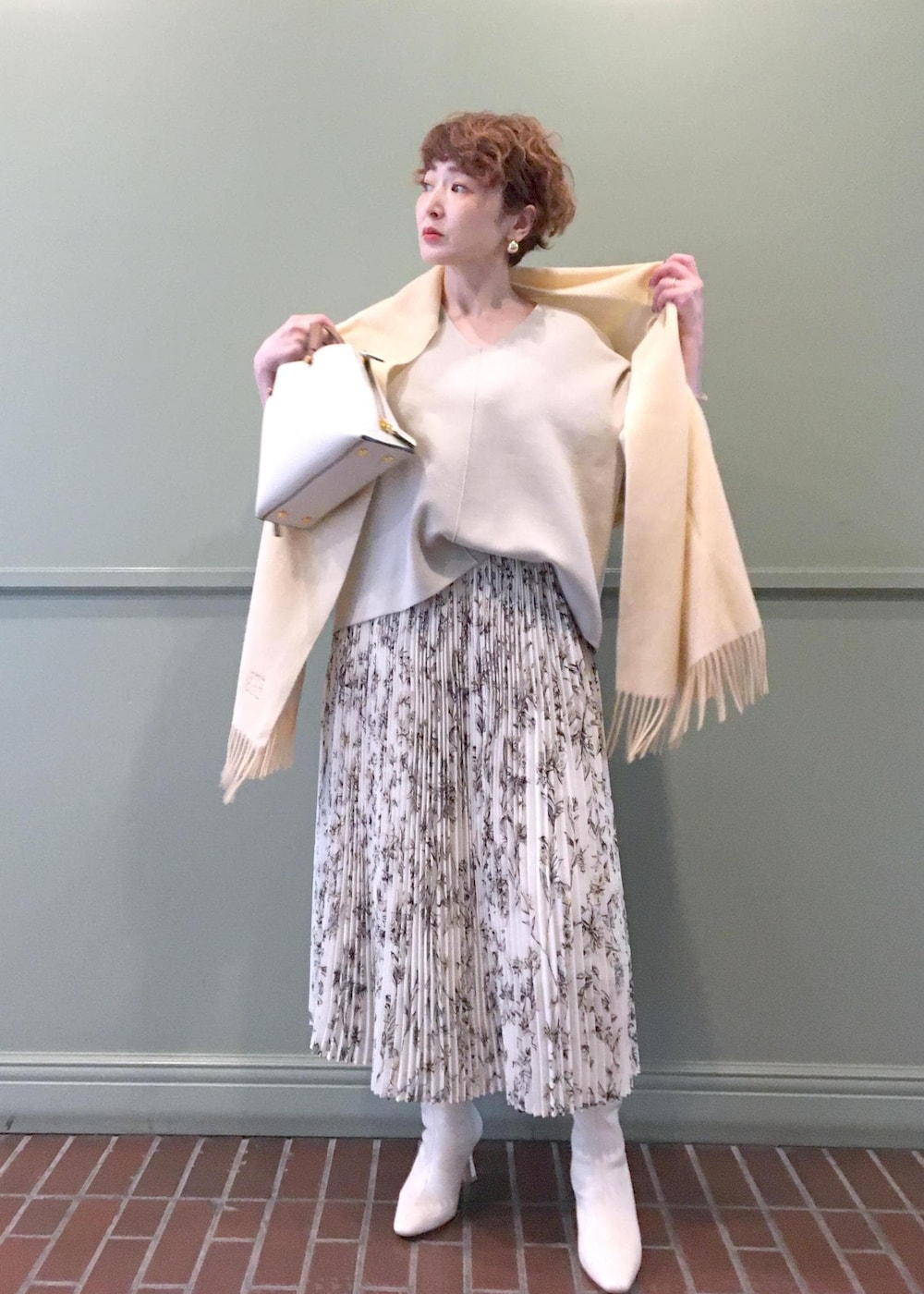 ホワイト系のハンドバッグ、ホワイト系のブーツ、ベージュ系のニット/セーターを着用したレディースの秋コーディネートの2枚目の写真