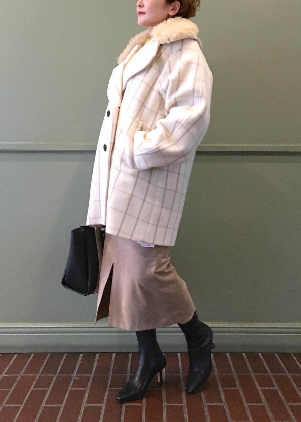 ブラック系のトートバッグ、ブラック系のブーツ、ホワイト系のチェスターコートを着用したレディースの秋コーディネートの4枚目の写真