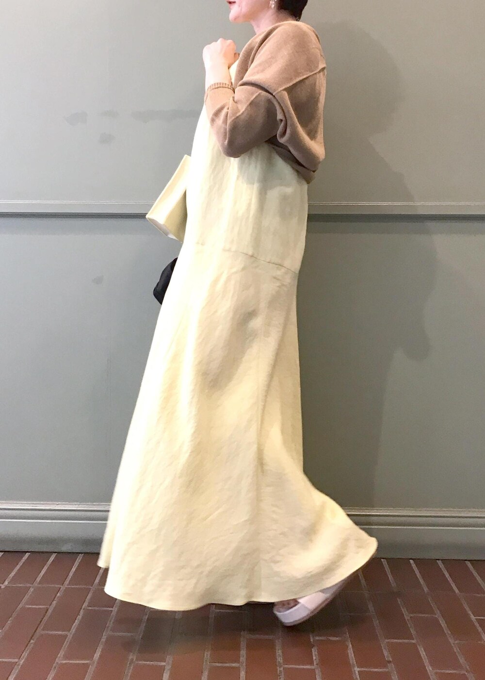 ベージュ系のショルダーバッグ、ベージュ系のサンダル、イエロー系のワンピースを着用したレディースの春コーディネートの6枚目の写真