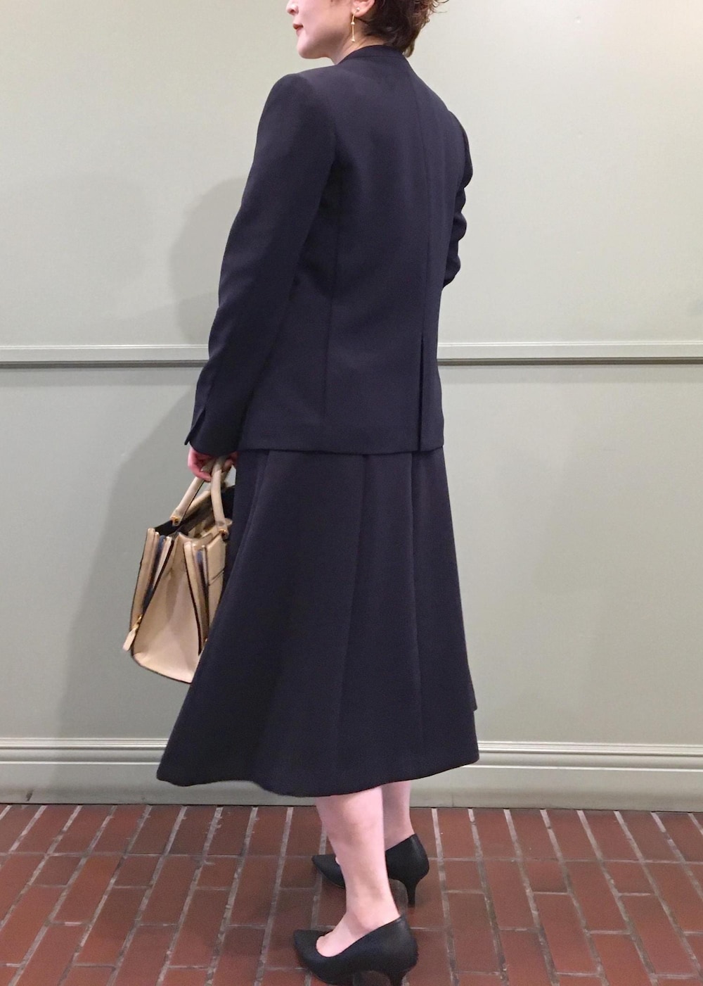 ベージュ系のハンドバッグ、ブルー系のワンピース、ブルー系のノーカラージャケットを着用したレディースの冬コーディネートの6枚目の写真