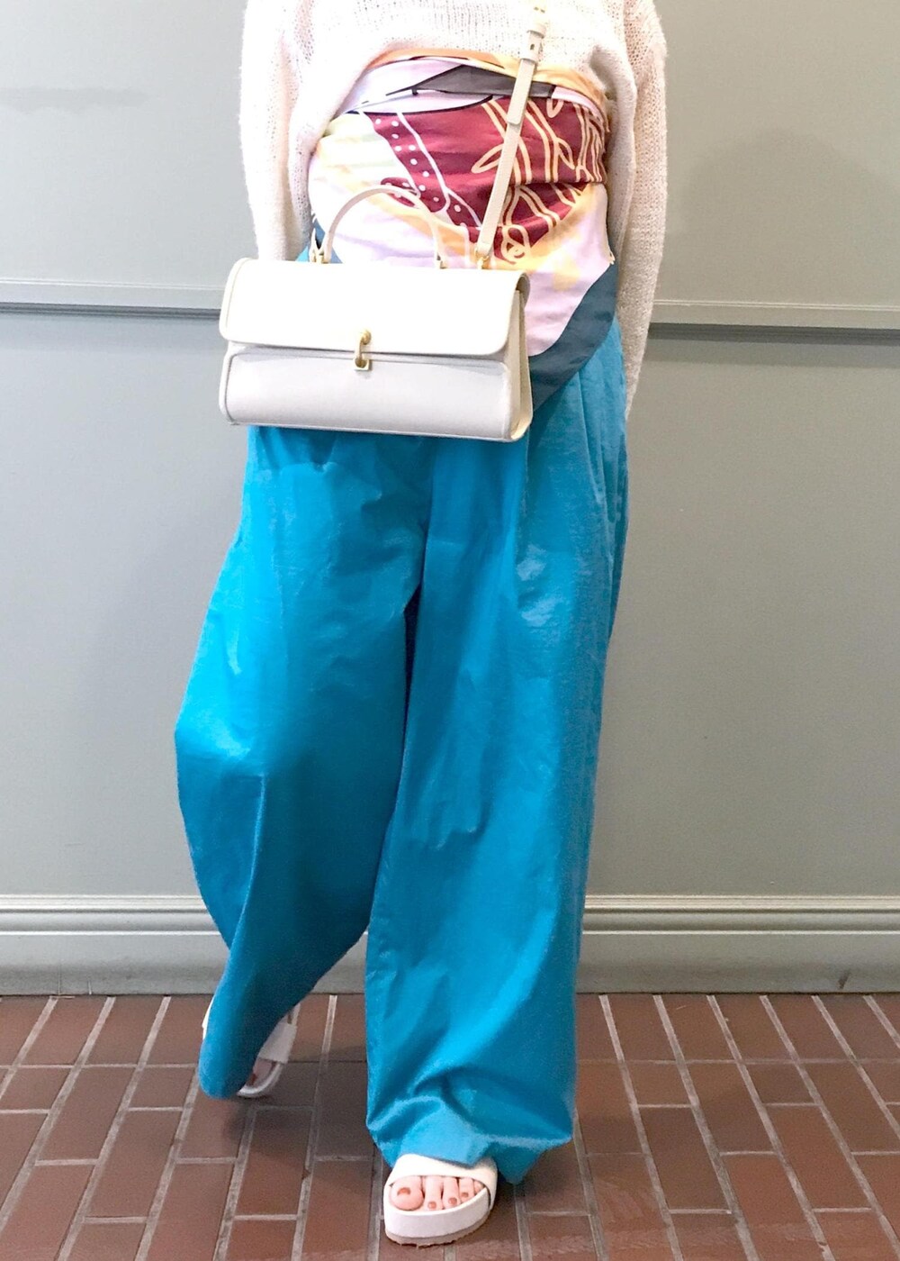 ベージュ系のショルダーバッグ、ホワイト系のニット/セーター、ブルー系のつなぎ/オールインワンを着用したレディースの春コーディネートの5枚目の写真