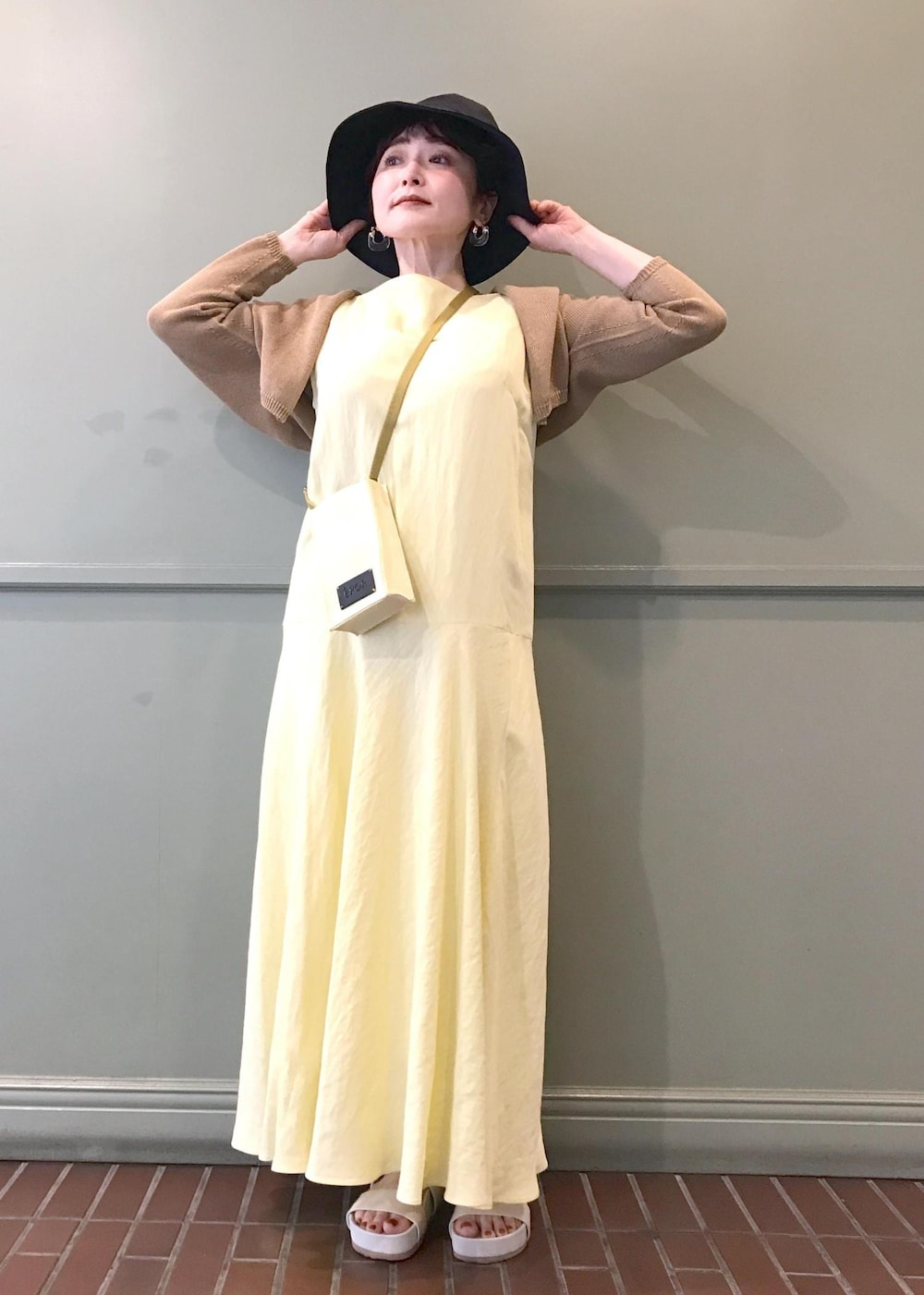 ベージュ系のショルダーバッグ、ベージュ系のサンダル、イエロー系のワンピースを着用したレディースの春コーディネートの3枚目の写真