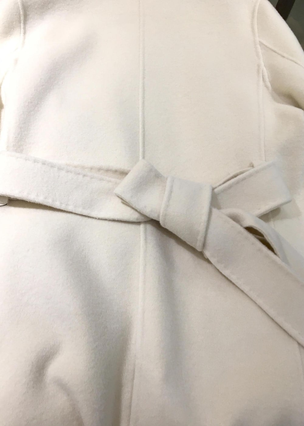 ブラック系のハンドバッグ、ホワイト系のチェスターコート、ベージュ系のシャツ/ブラウスを着用したレディースの秋コーディネートの5枚目の写真