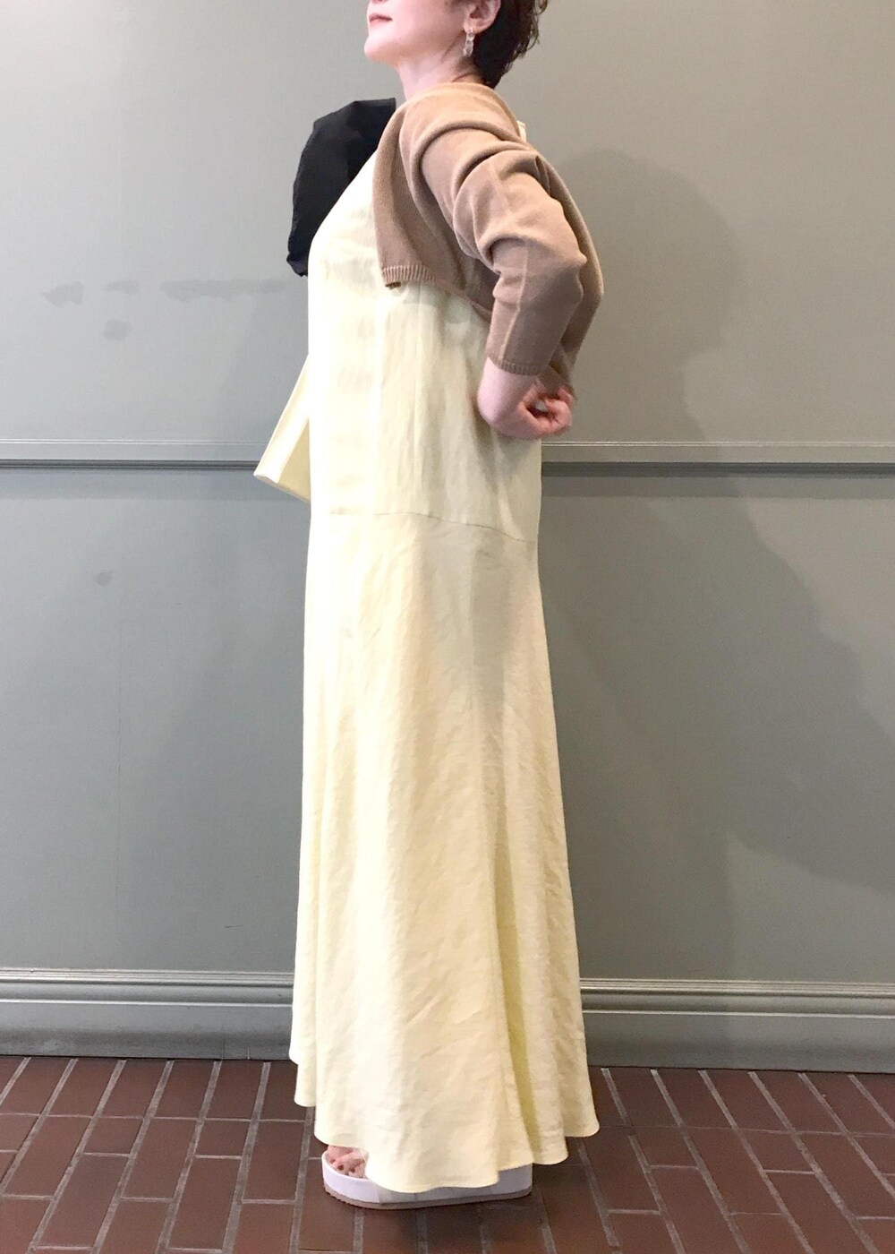 ベージュ系のショルダーバッグ、ベージュ系のサンダル、イエロー系のワンピースを着用したレディースの春コーディネートの5枚目の写真