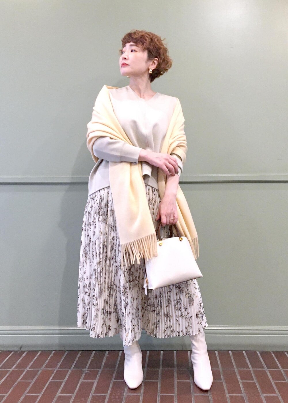 ホワイト系のハンドバッグ、ホワイト系のブーツ、ベージュ系のニット/セーターを着用したレディースの秋コーディネートの4枚目の写真