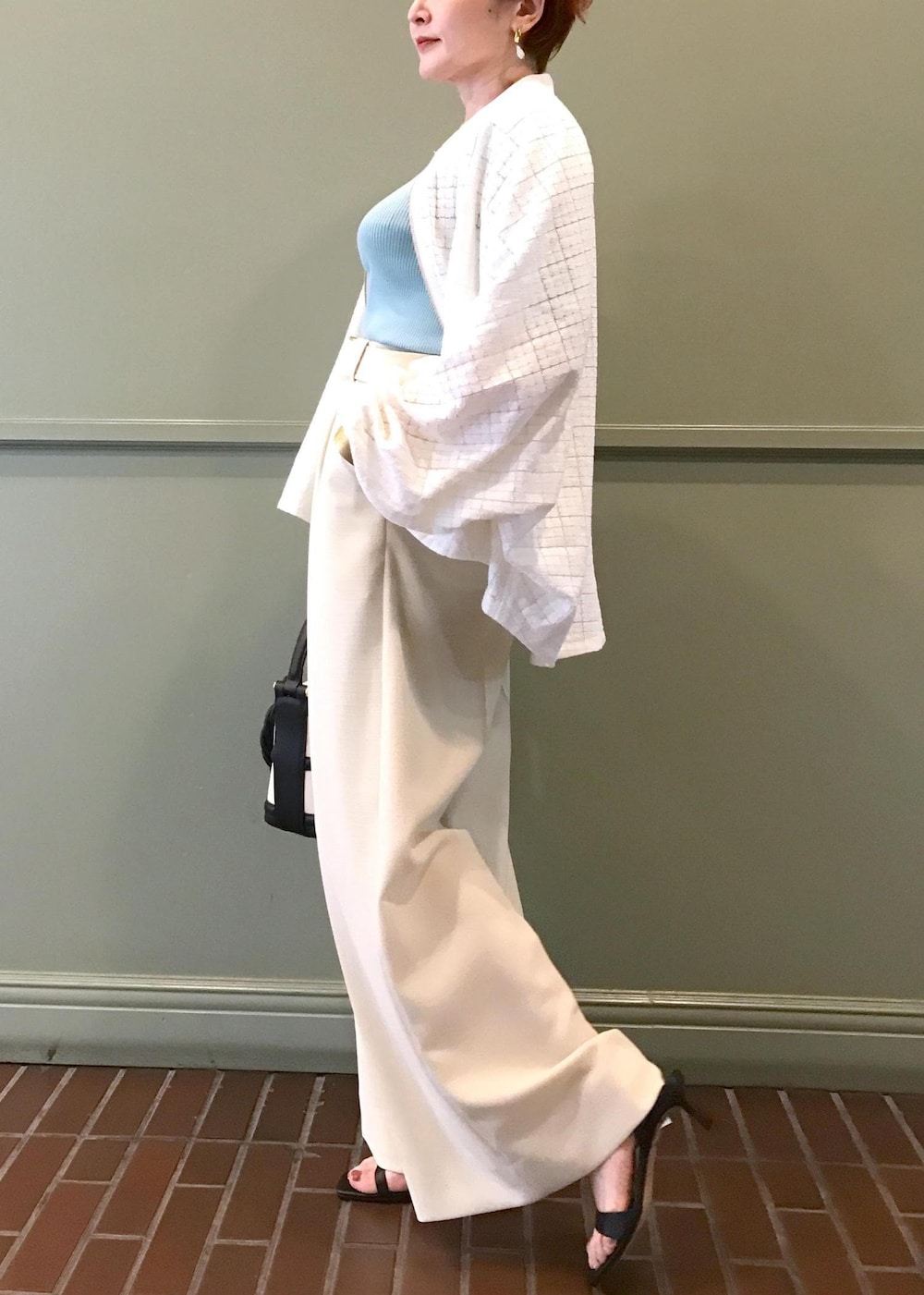 ブラック系のハンドバッグ、ブラック系のサンダル、ホワイト系のブルゾンを着用したレディースの春コーディネートの3枚目の写真