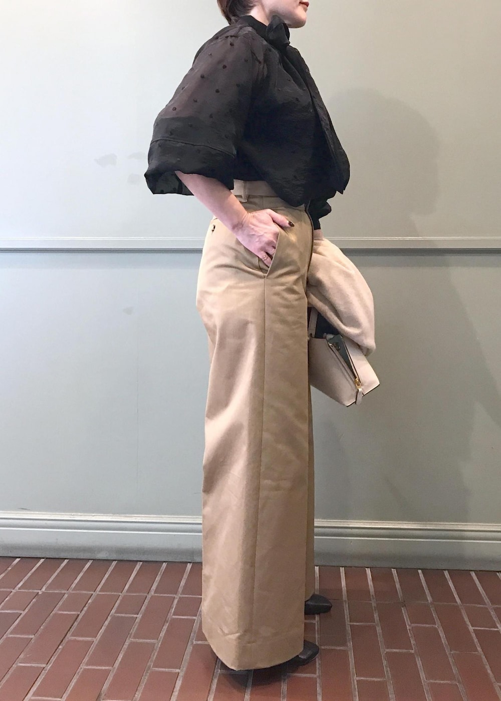 ホワイト系のハンドバッグ、ブラック系のブーツ、ベージュ系のチノパンツを着用したレディースの秋コーディネートの7枚目の写真