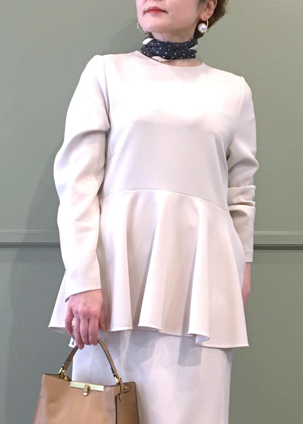 ブラック系のパンプス、ベージュ系のショルダーバッグ、ベージュ系のスカートを着用したレディースの冬コーディネートの5枚目の写真