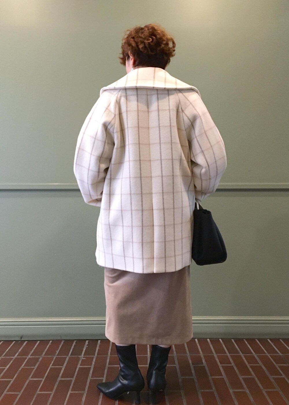 ブラック系のトートバッグ、ブラック系のブーツ、ホワイト系のチェスターコートを着用したレディースの秋コーディネートの3枚目の写真