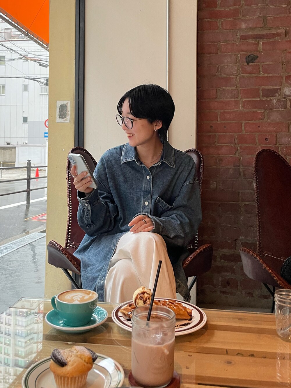 ブルー系のトップス、ホワイト系のデニムパンツ、ブラック系のハンドバッグを着用したレディースの春コーディネートの2枚目の写真