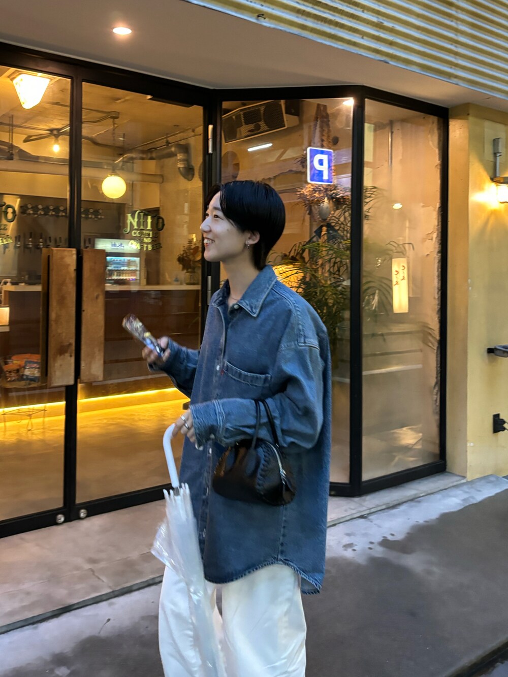 ブルー系のトップス、ホワイト系のデニムパンツ、ブラック系のハンドバッグを着用したレディースの春コーディネートの4枚目の写真
