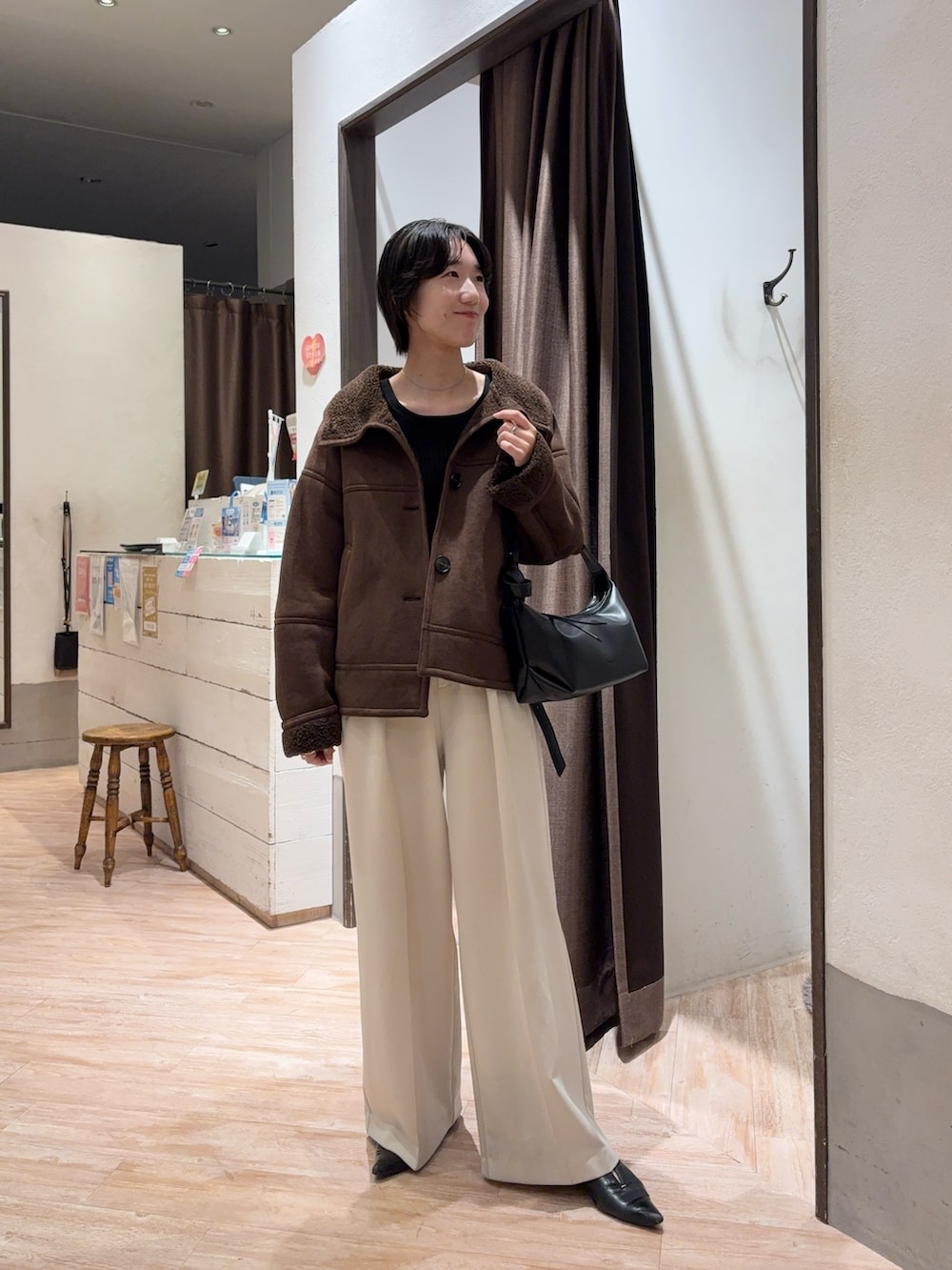 ブラウン系のその他アウター、ホワイト系のその他パンツ、ブラック系のショルダーバッグを着用したレディースの秋コーディネートの2枚目の写真