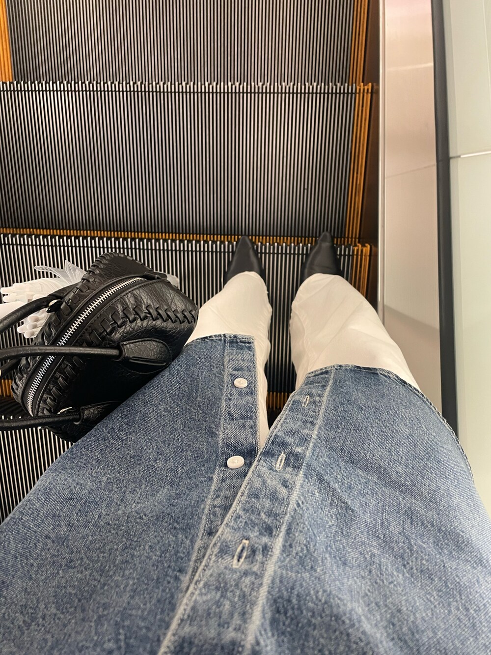 ブルー系のトップス、ホワイト系のデニムパンツ、ブラック系のハンドバッグを着用したレディースの春コーディネートの3枚目の写真