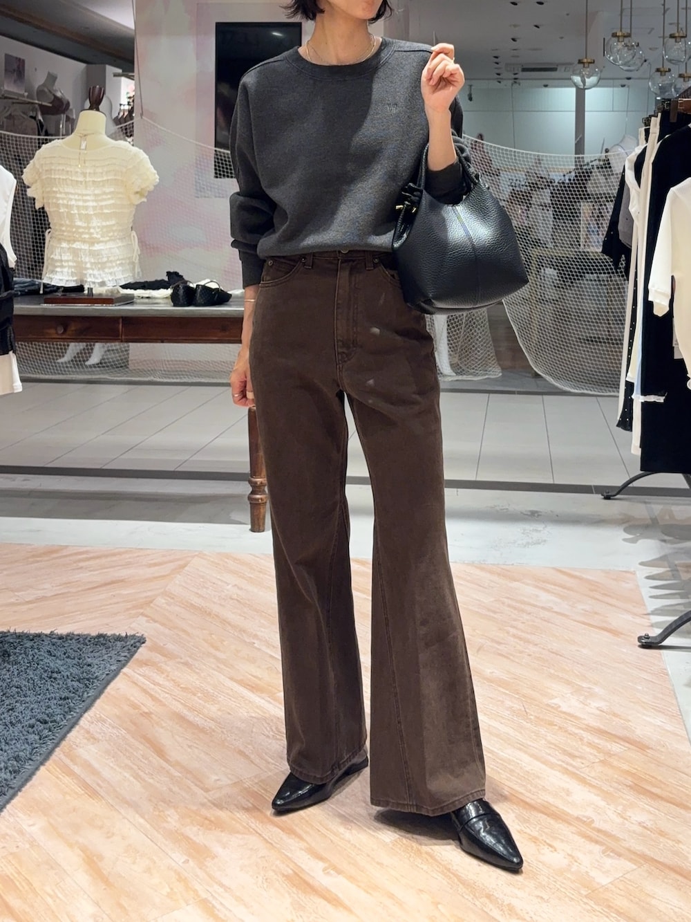 グレー系のニット/セーター、ブラウン系のデニムパンツ、ブラック系のショルダーバッグを着用したレディースの秋コーディネートの3枚目の写真