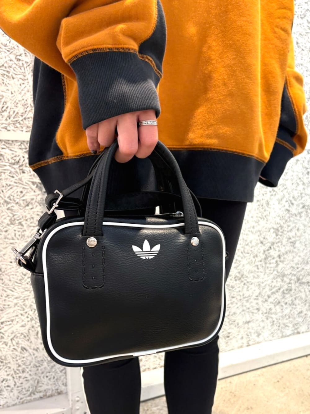 ブラック系のショルダーバッグ、ブラウン系のトップス、ブラウン系のスニーカーを着用したレディースの秋コーディネートの4枚目の写真