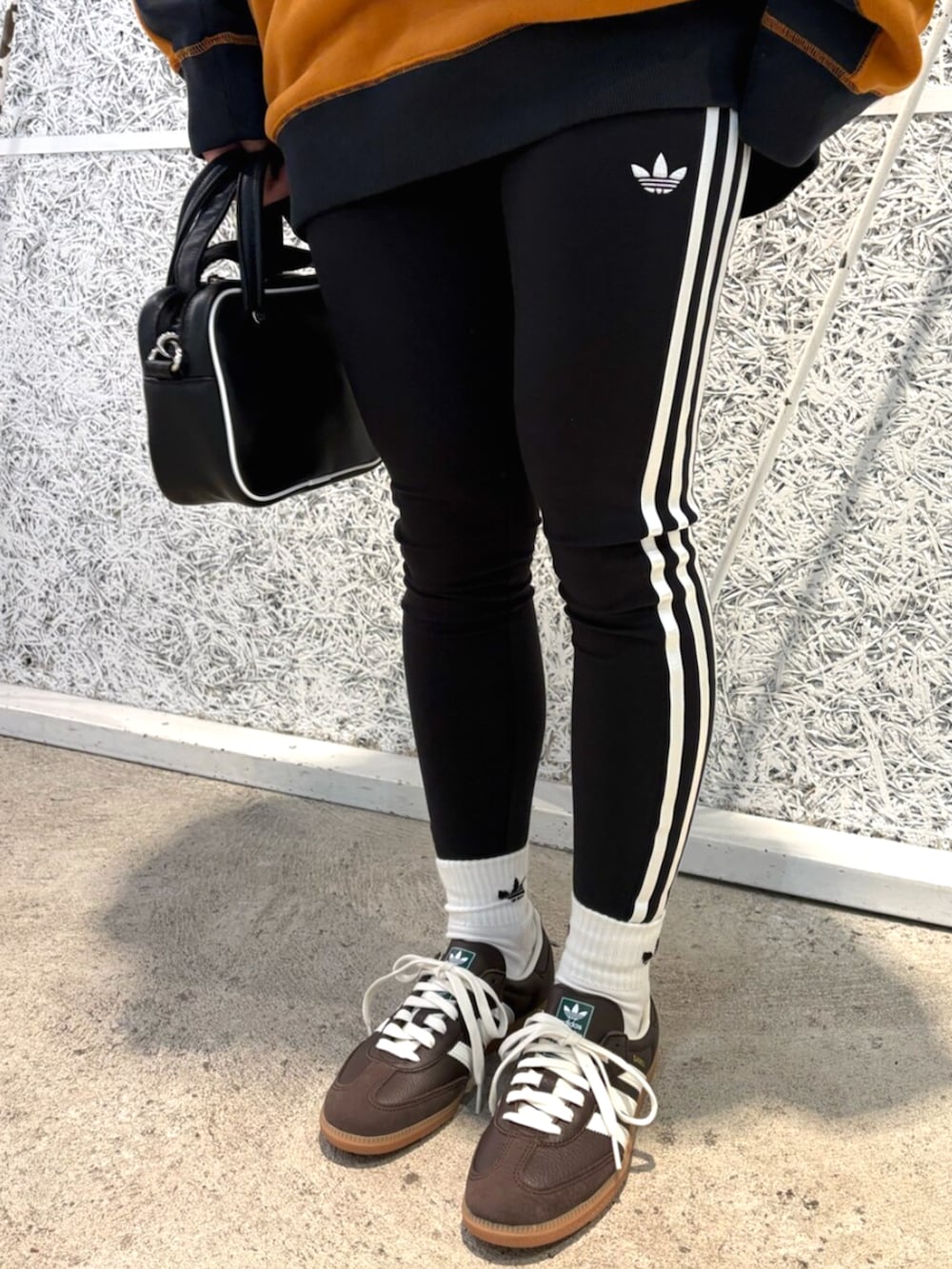 ブラック系のショルダーバッグ、ブラウン系のトップス、ブラウン系のスニーカーを着用したレディースの秋コーディネートの5枚目の写真