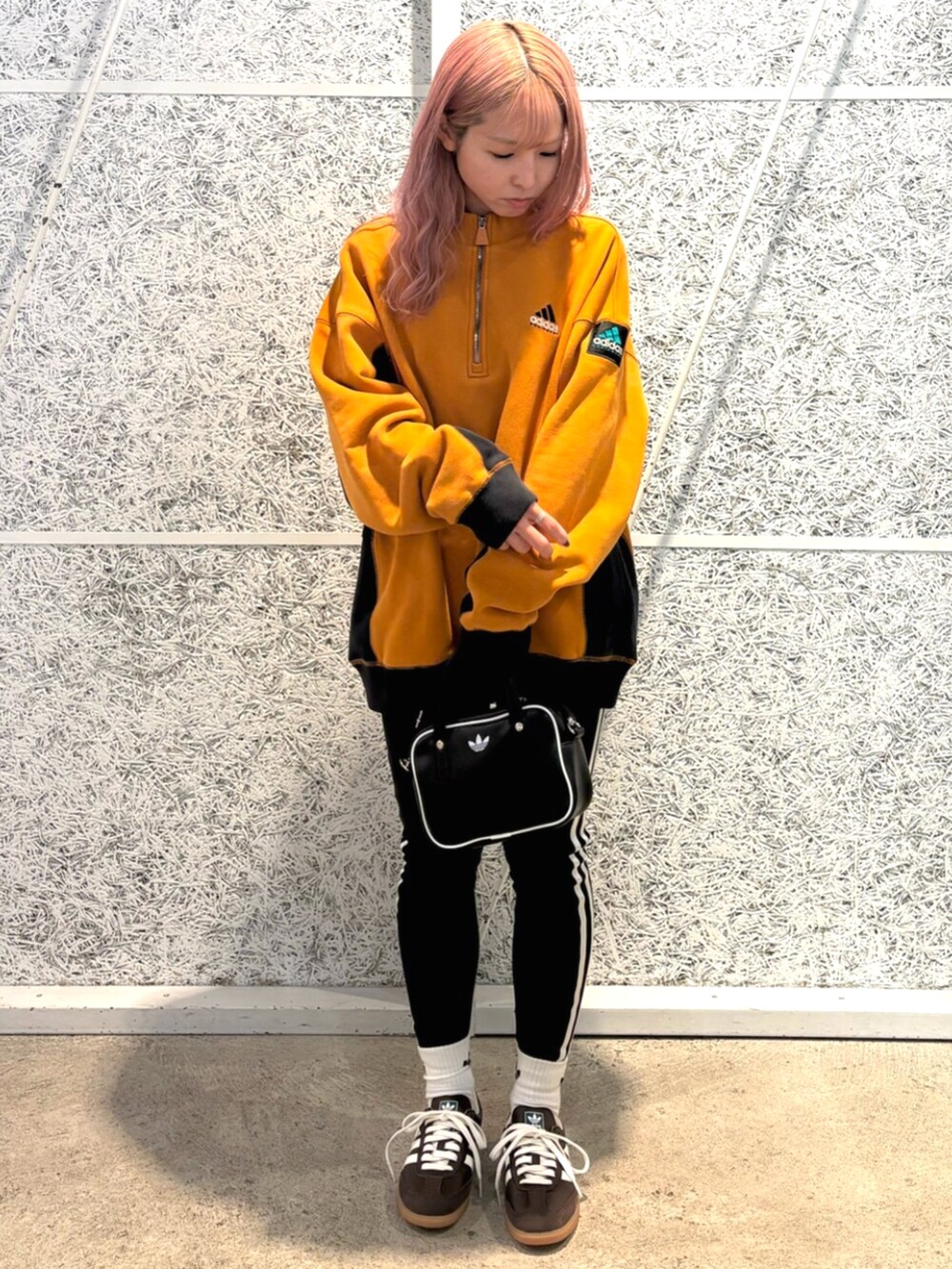 ブラック系のショルダーバッグ、ブラウン系のトップス、ブラウン系のスニーカーを着用したレディースの秋コーディネートの2枚目の写真