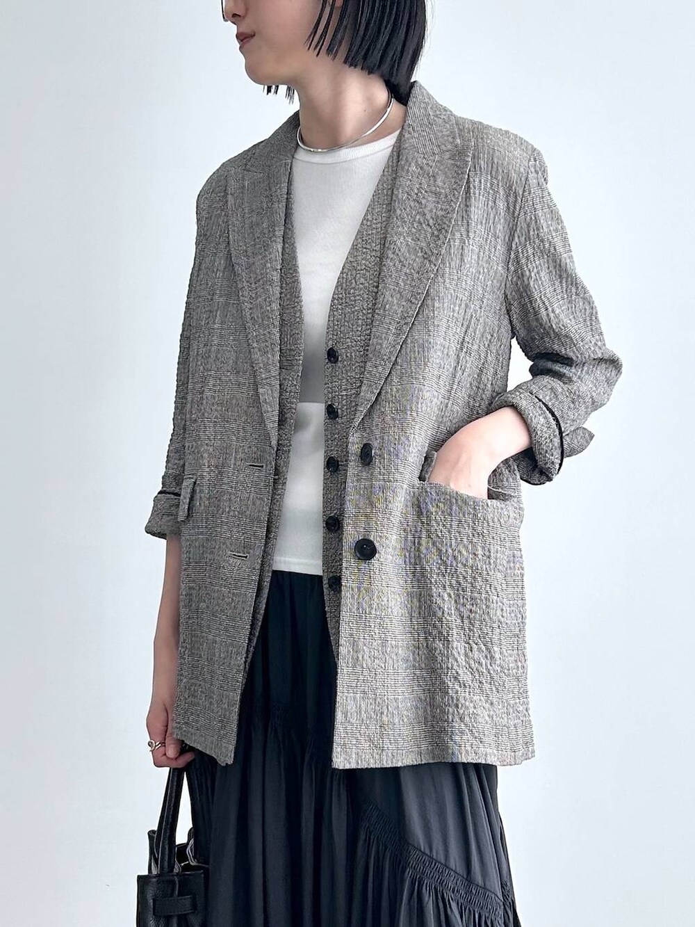 ブラック系のハンドバッグ、ブラック系のテーラードジャケット、ブラック系のベストを着用したレディースの冬コーディネートの2枚目の写真