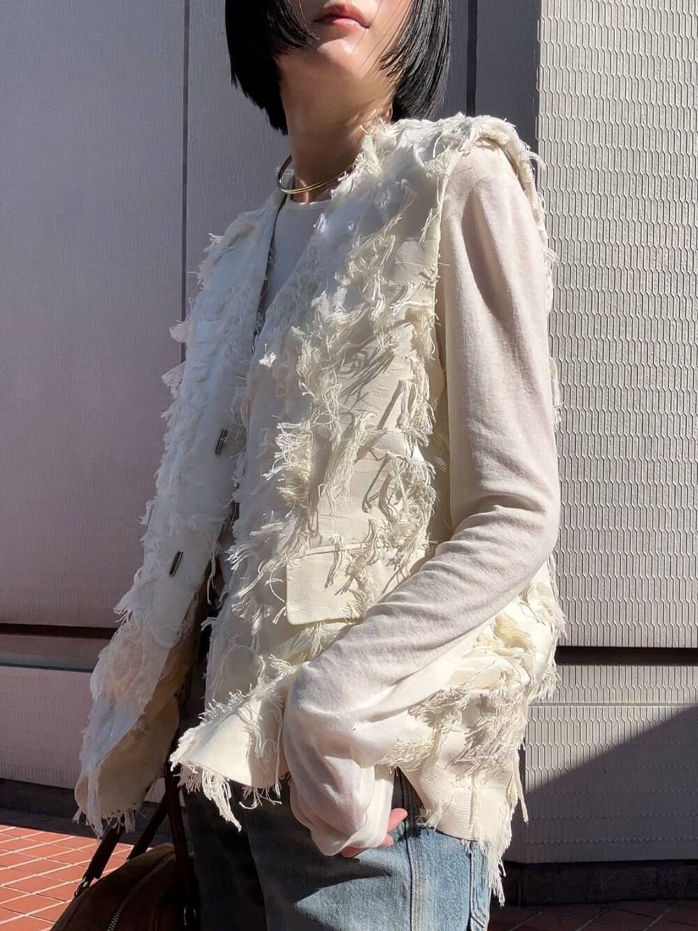 ホワイト系のTシャツ/カットソー、ホワイト系のベスト、ブルー系のデニムパンツを着用したレディースの冬コーディネートの4枚目の写真