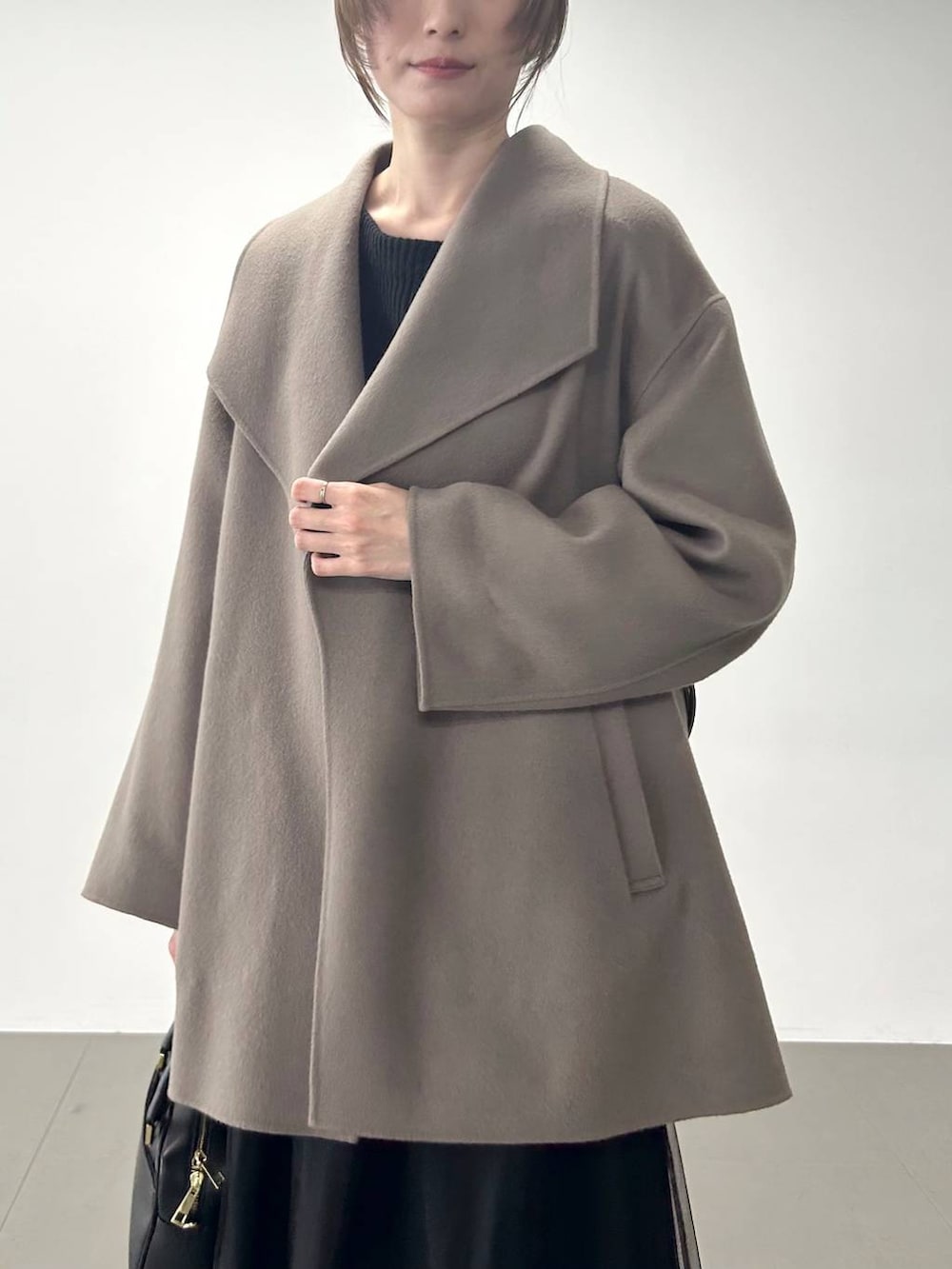 ブラック系のボストンバッグ、ブラウン系のピーコート、ブラック系のニット/セーターを着用したレディースの冬コーディネートの4枚目の写真