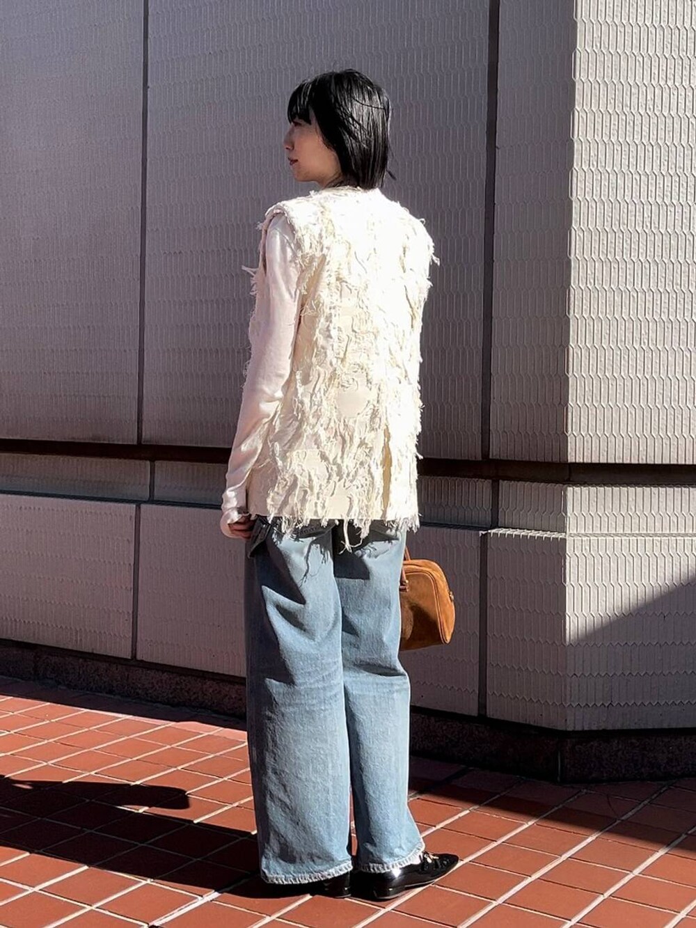 ホワイト系のTシャツ/カットソー、ホワイト系のベスト、ブルー系のデニムパンツを着用したレディースの冬コーディネートの3枚目の写真