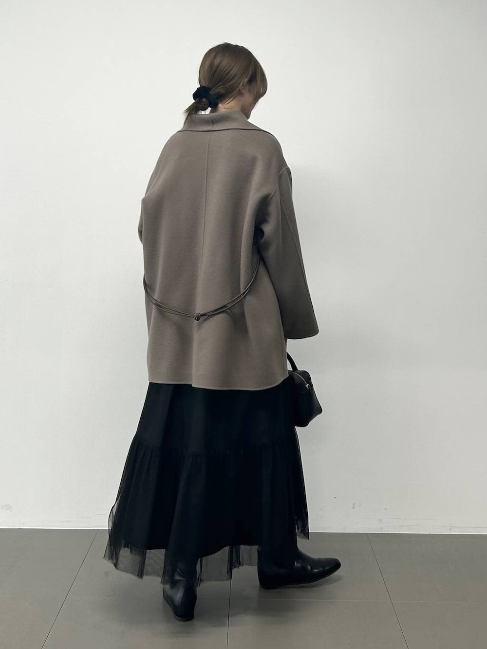 ブラック系のボストンバッグ、ブラウン系のピーコート、ブラック系のニット/セーターを着用したレディースの冬コーディネートの3枚目の写真