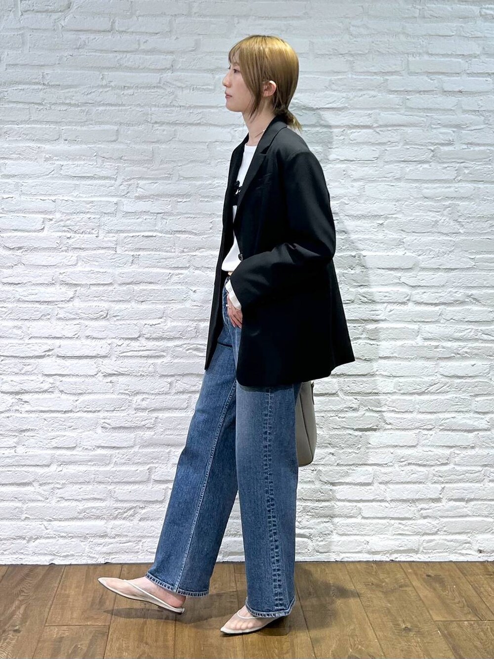 ベージュ系のパンプス、ブラック系のテーラードジャケット、ブルー系のデニムパンツを着用したレディースの冬コーディネートの2枚目の写真