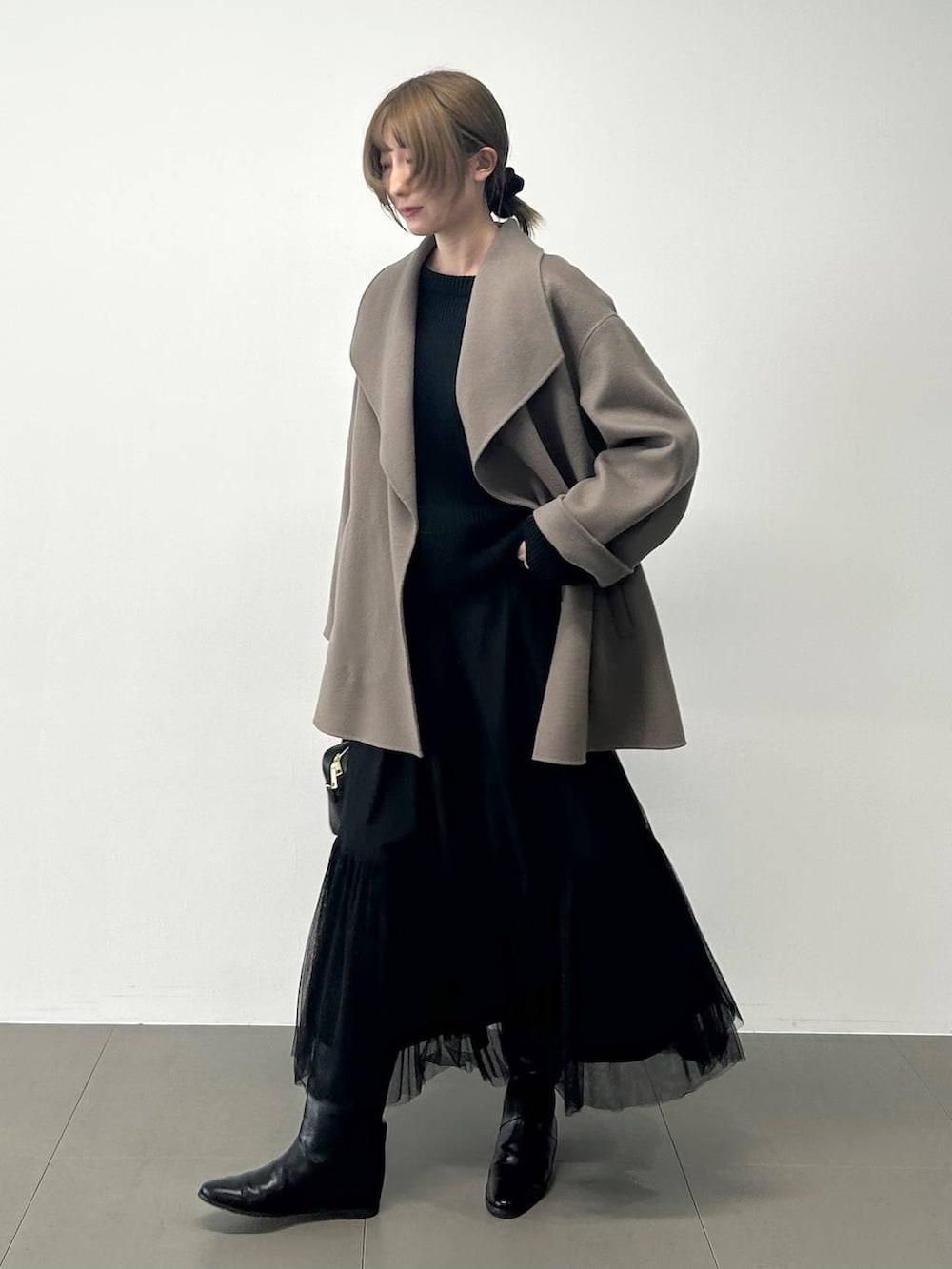 ブラック系のボストンバッグ、ブラウン系のピーコート、ブラック系のニット/セーターを着用したレディースの冬コーディネートの6枚目の写真