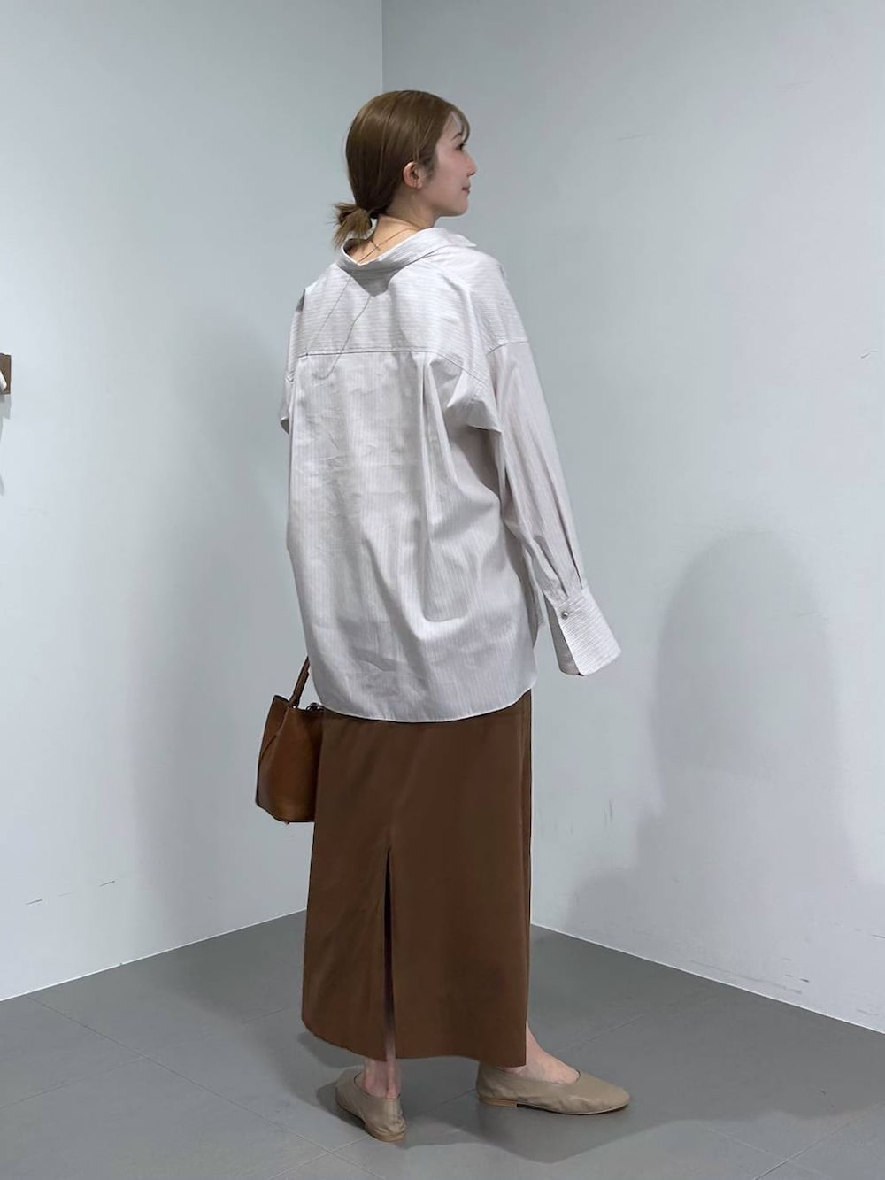 イエロー系のスカート、ベージュ系のシャツ/ブラウス、ブラウン系のショルダーバッグを着用したレディースの冬コーディネートの3枚目の写真