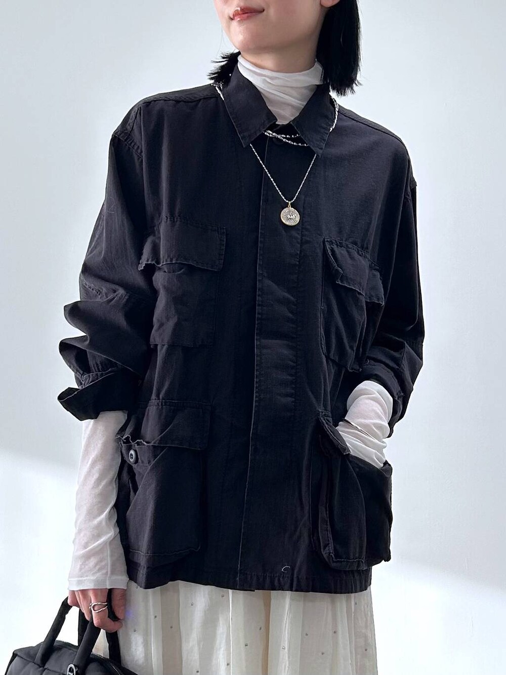 ブラック系のミリタリージャケット、ホワイト系のTシャツ/カットソー、ホワイト系のスカートを着用したレディースの冬コーディネートの4枚目の写真